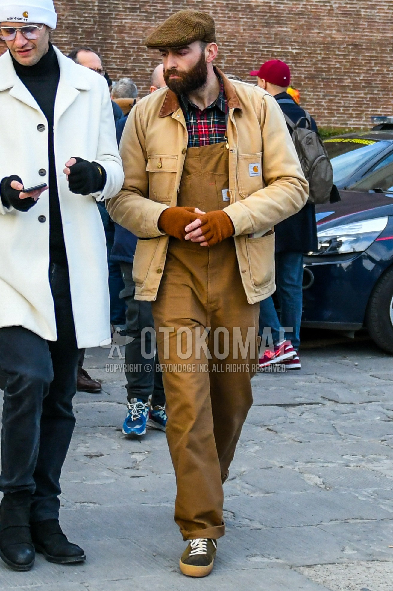 Men's winter outfit with brown plain hunting cap, brown plain coverall, brown plain jumpsuit, red multi-color check shirt, brown low-cut sneakers.