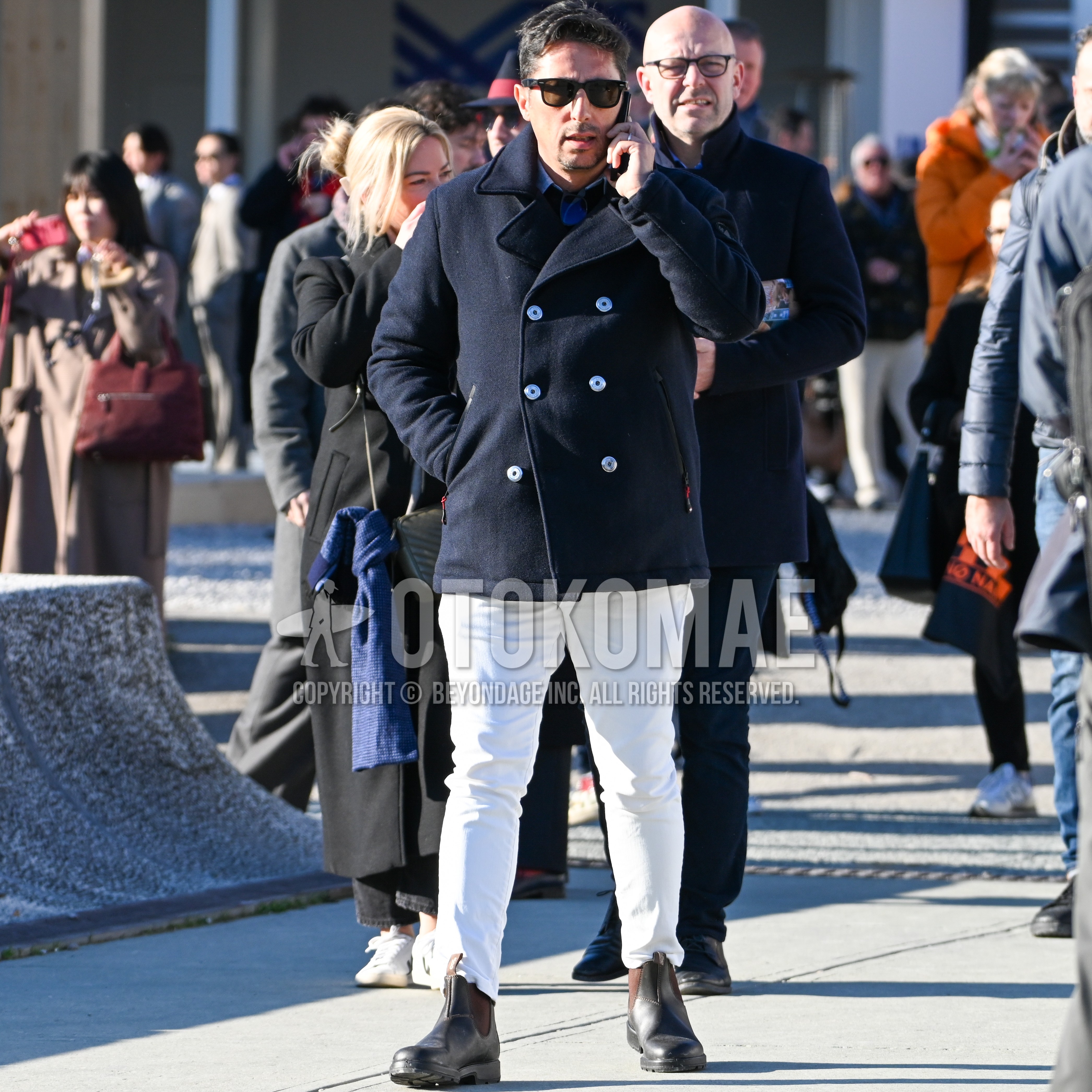 Men's autumn winter outfit with black plain sunglasses, navy plain p coat, light blue plain shirt, white plain skinny pants, brown side-gore boots.