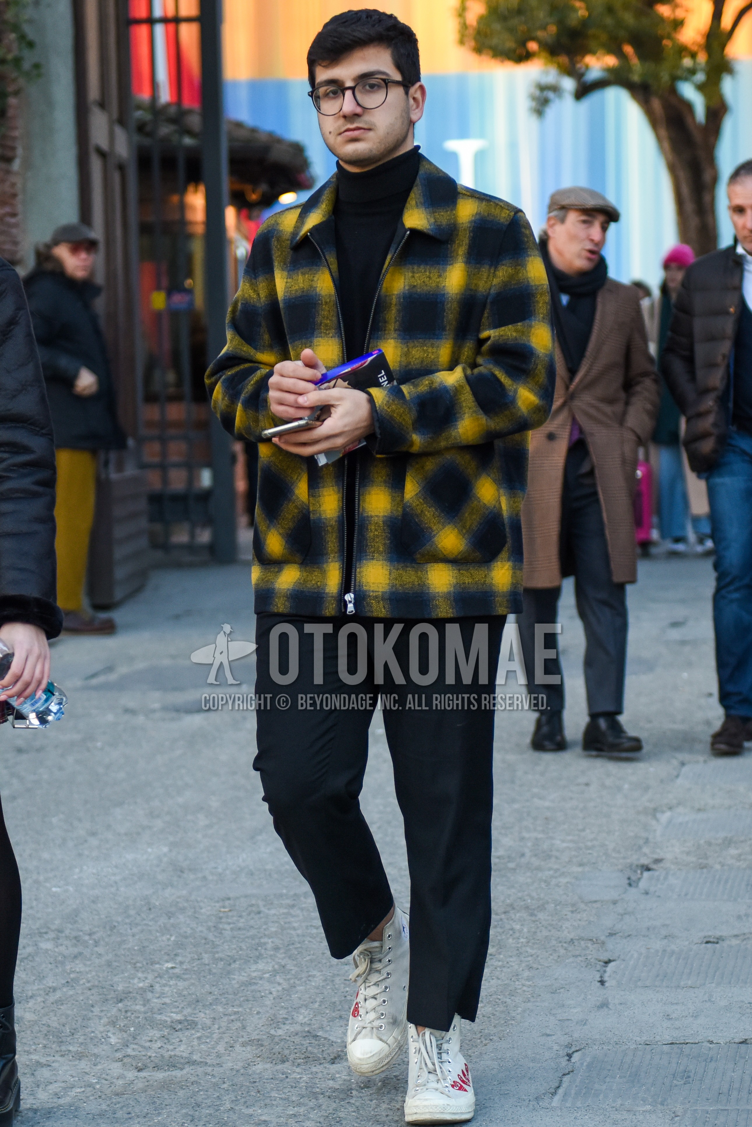 Men's autumn winter outfit with brown tortoiseshell glasses, yellow navy check shirt jacket, navy plain turtleneck knit, gray plain slacks, gray plain cropped pants, white high-cut sneakers.