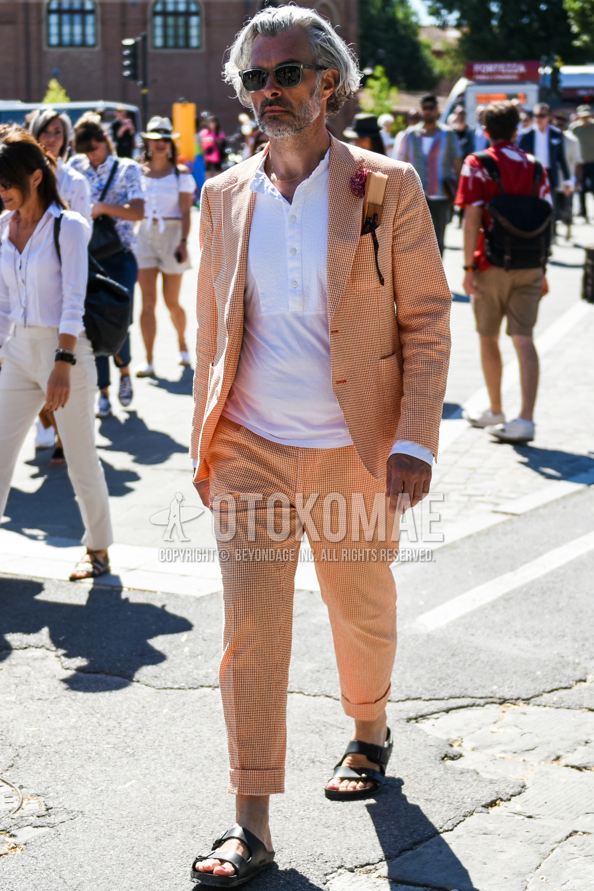 Men's spring summer outfit with olive green clear plain sunglasses, white plain t-shirt, black leather sandals, orange check suit.