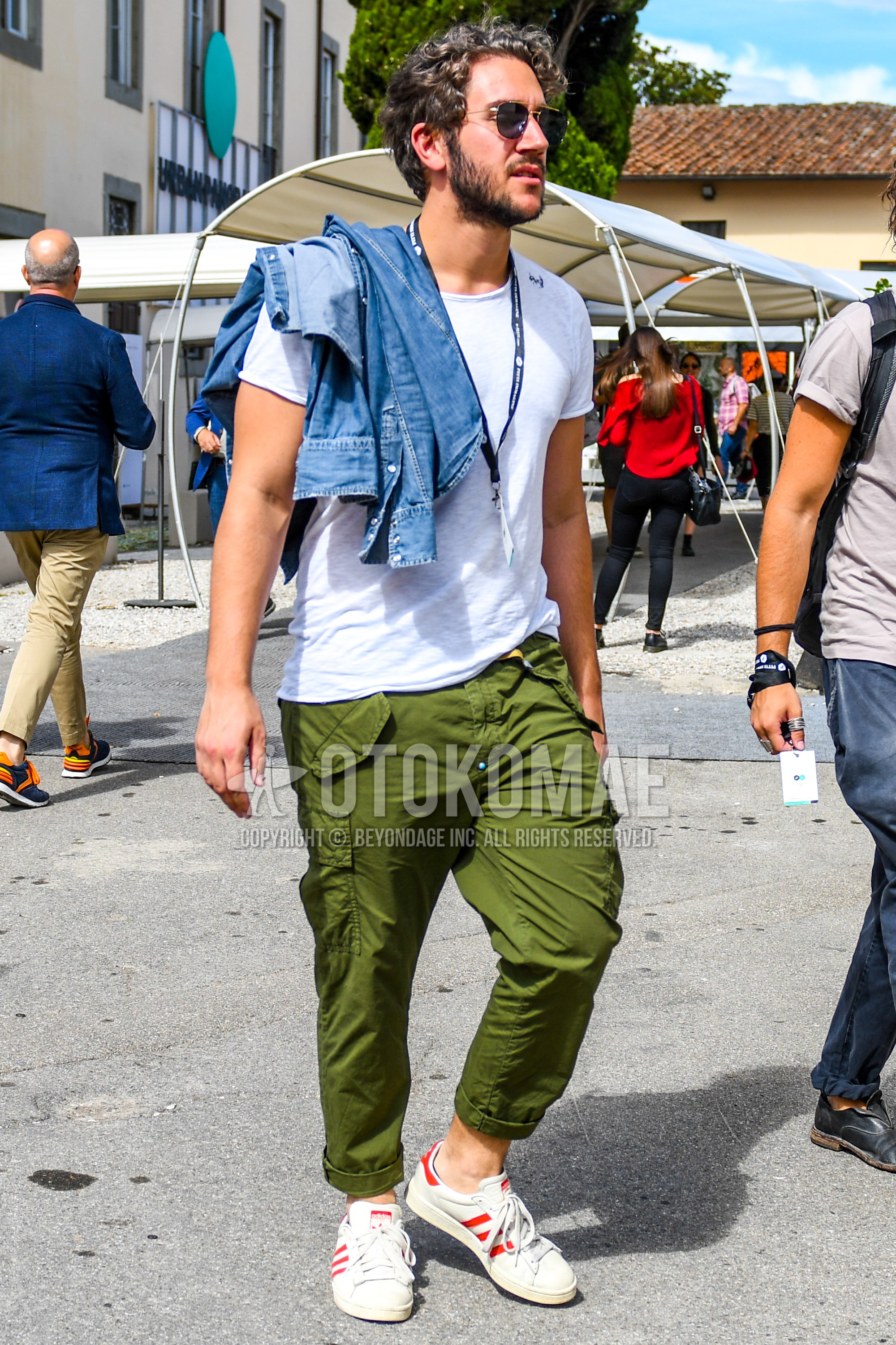 Men's summer outfit with gold plain sunglasses, white plain t-shirt, olive green plain cargo pants, white low-cut sneakers.