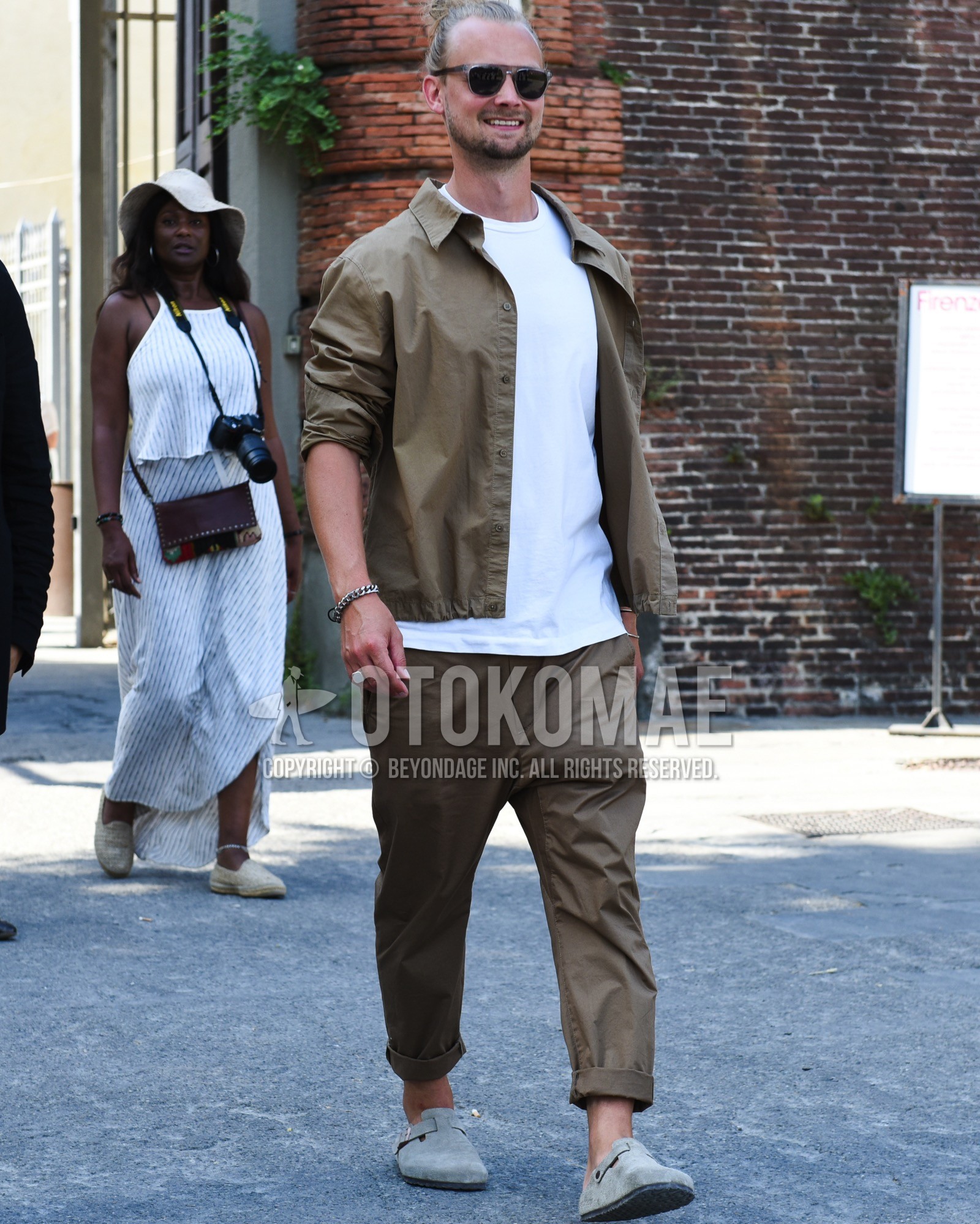 Men's spring summer outfit with gray plain sunglasses, white plain t-shirt, gray leather sandals, brown plain casual setup.