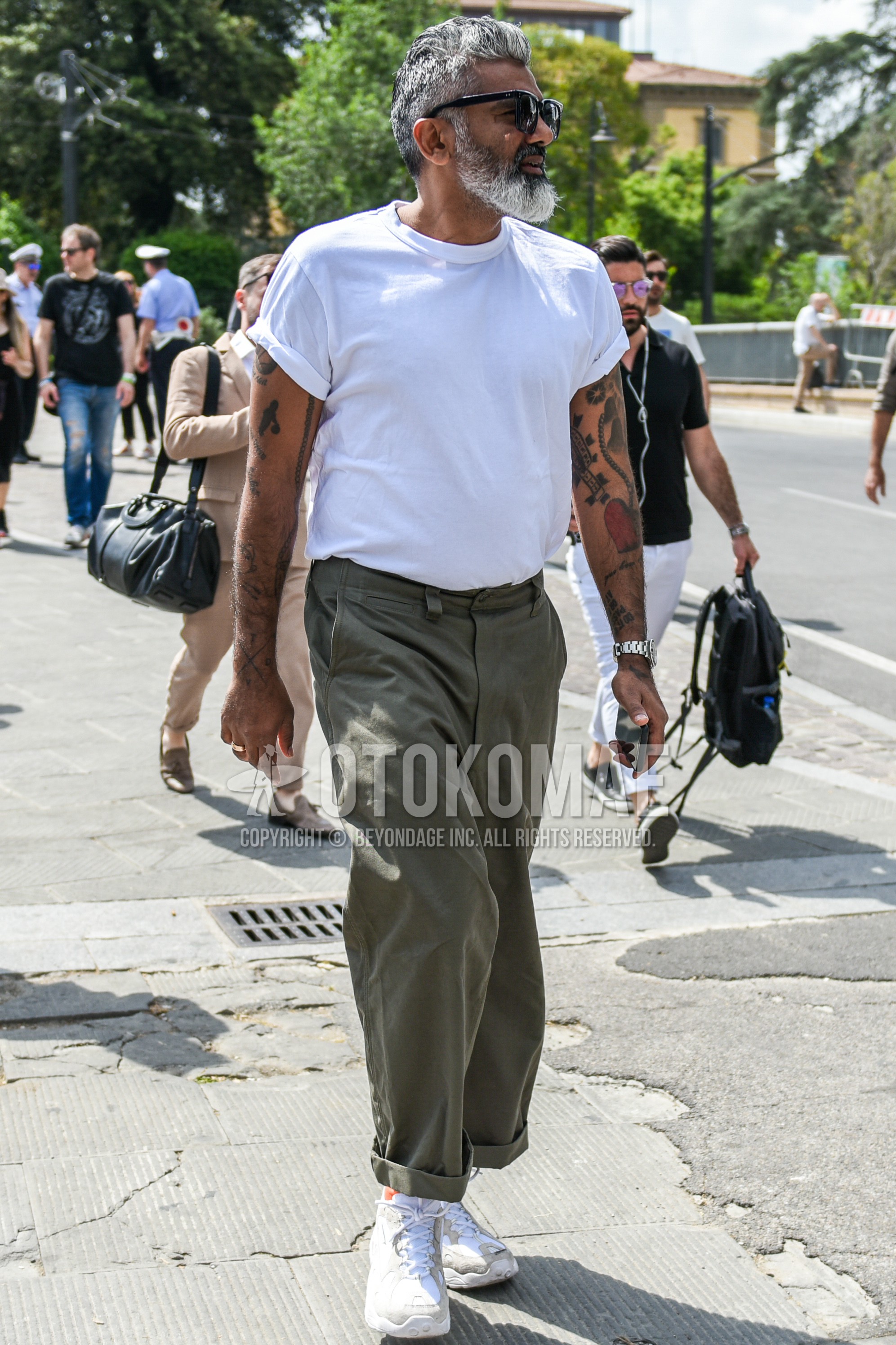 Men's summer outfit with black plain sunglasses, white plain t-shirt, olive green plain chinos, white low-cut sneakers.
