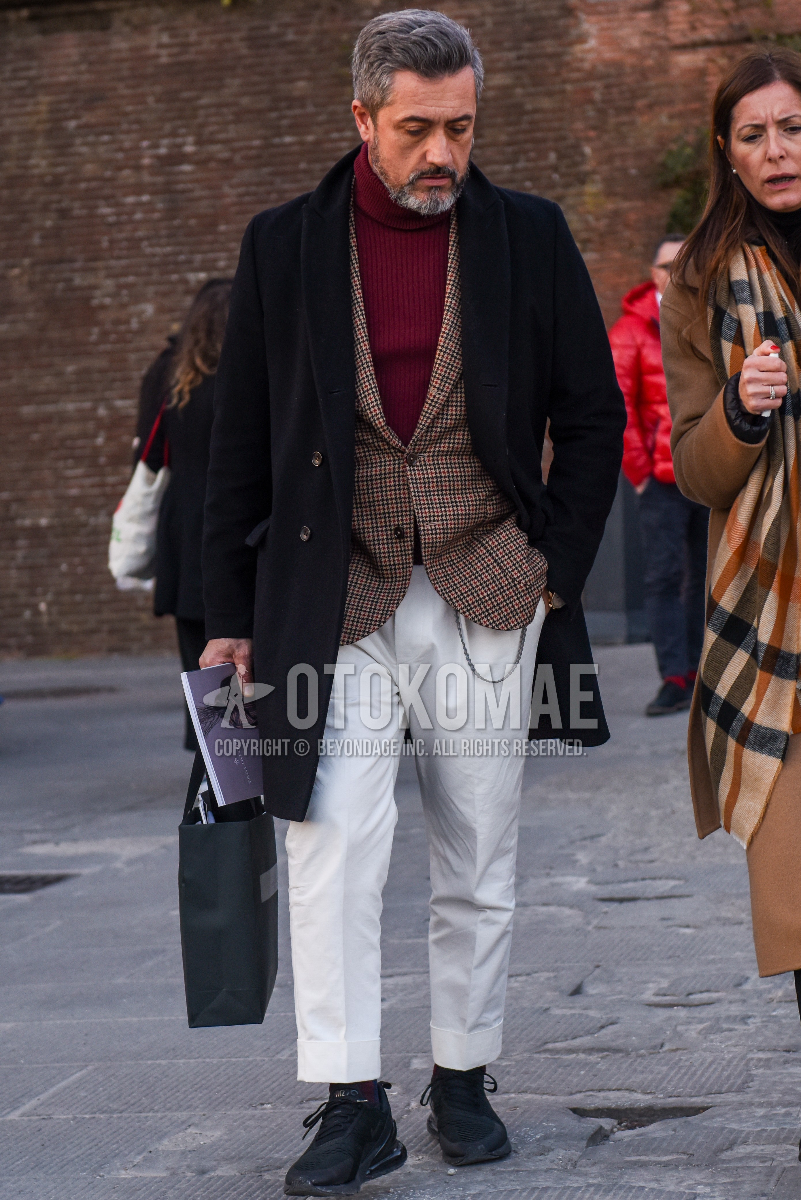 Men's autumn winter outfit with navy plain chester coat, red plain turtleneck knit, beige check tailored jacket, white plain cotton pants, white plain ankle pants, black low-cut sneakers.