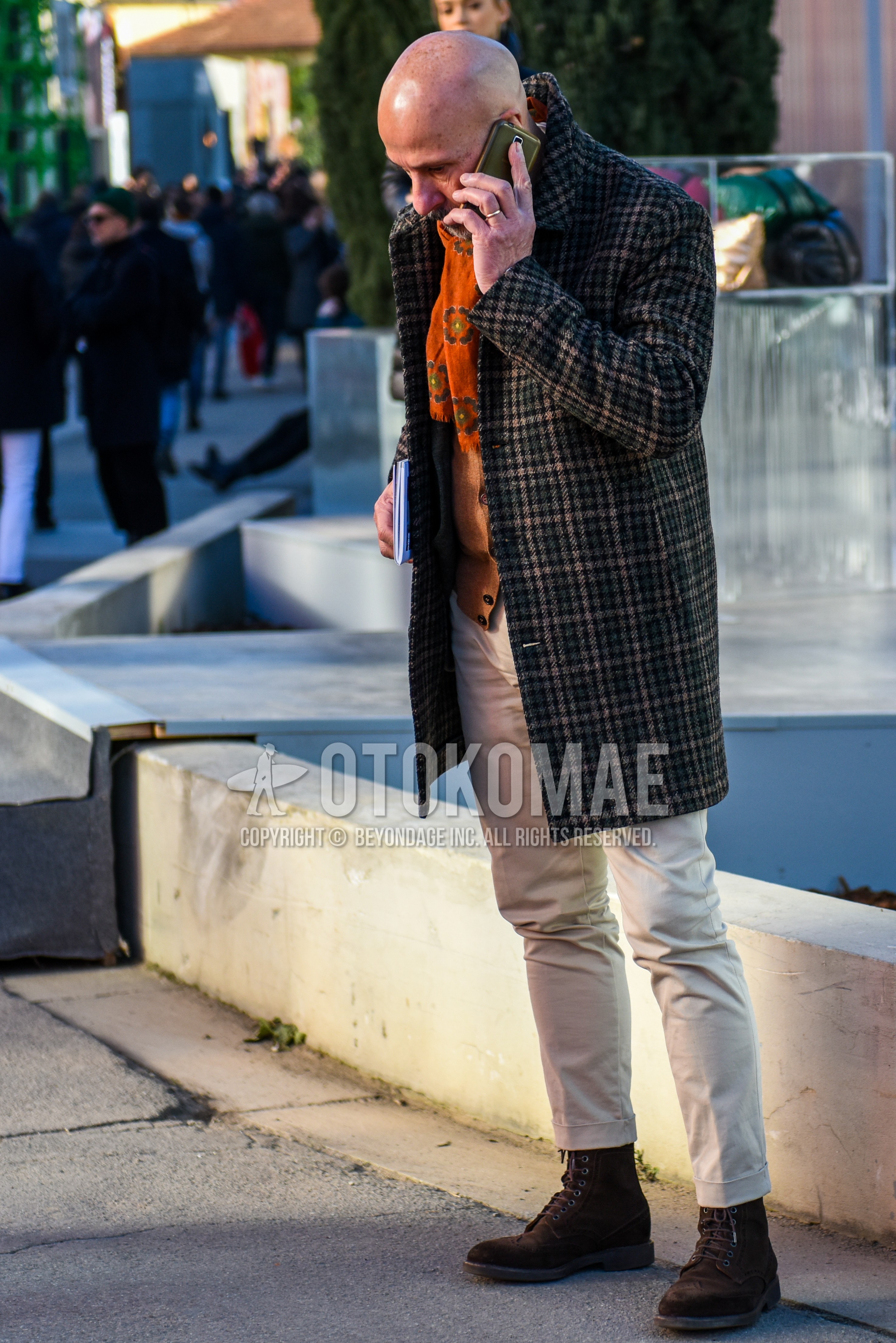 Men's winter outfit with orange scarf scarf, brown check stenkarrer coat, beige plain cardigan, beige plain chinos, brown  boots.