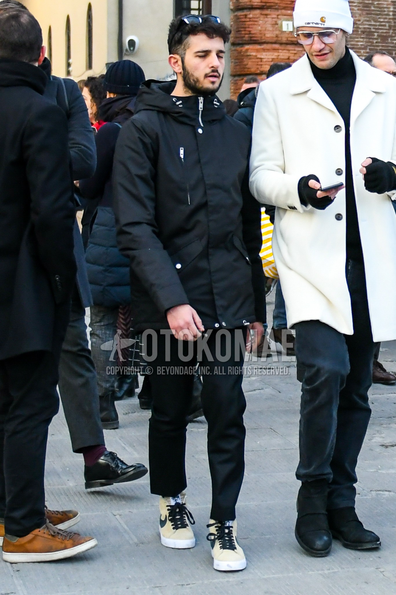 Men's winter outfit with black plain hooded coat, black plain ankle pants, beige high-cut sneakers.