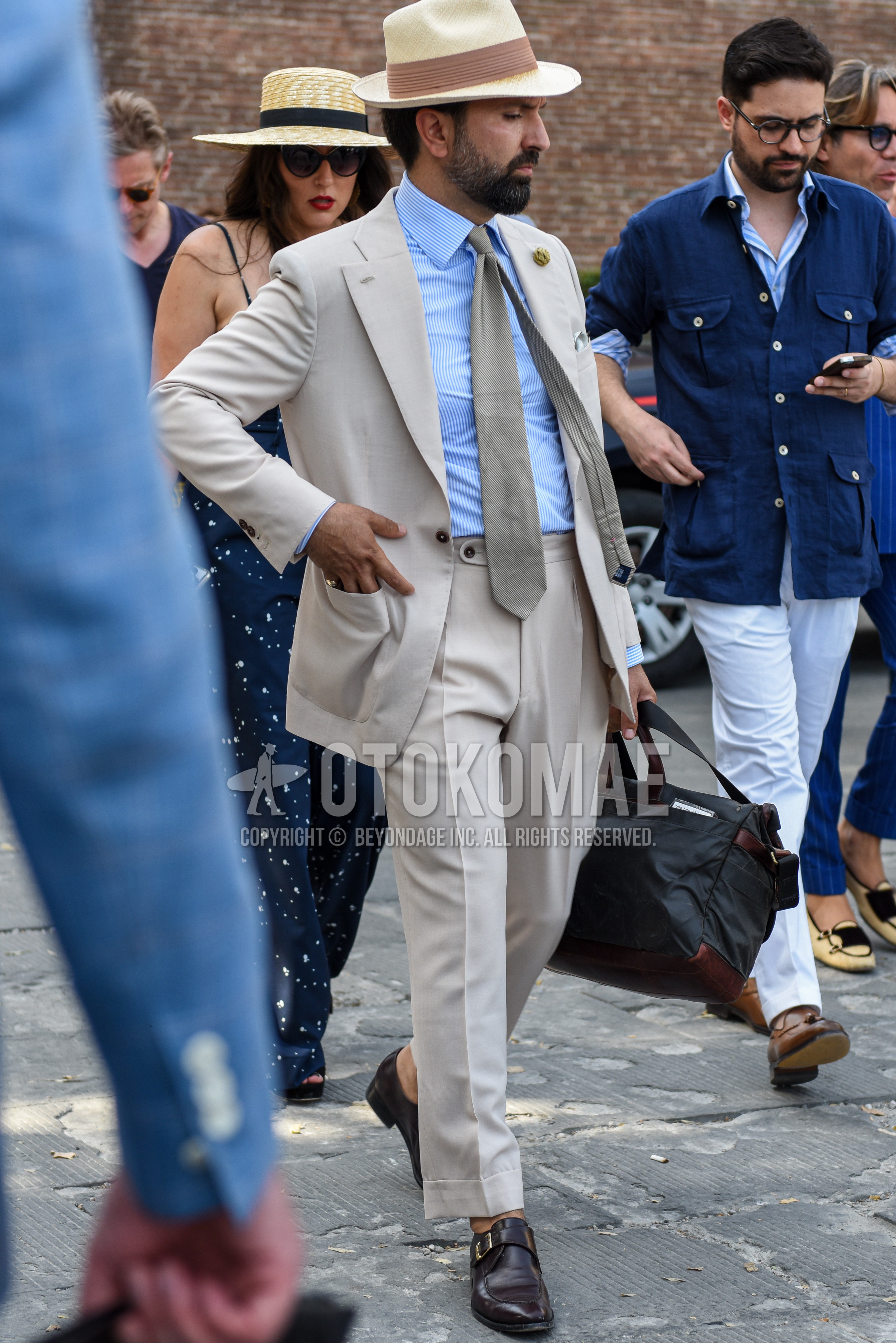 Men's spring summer autumn outfit with beige plain hat, light blue plain shirt, brown u-tip shoes leather shoes, dark gray plain boston bag, beige plain suit, gray plain necktie.