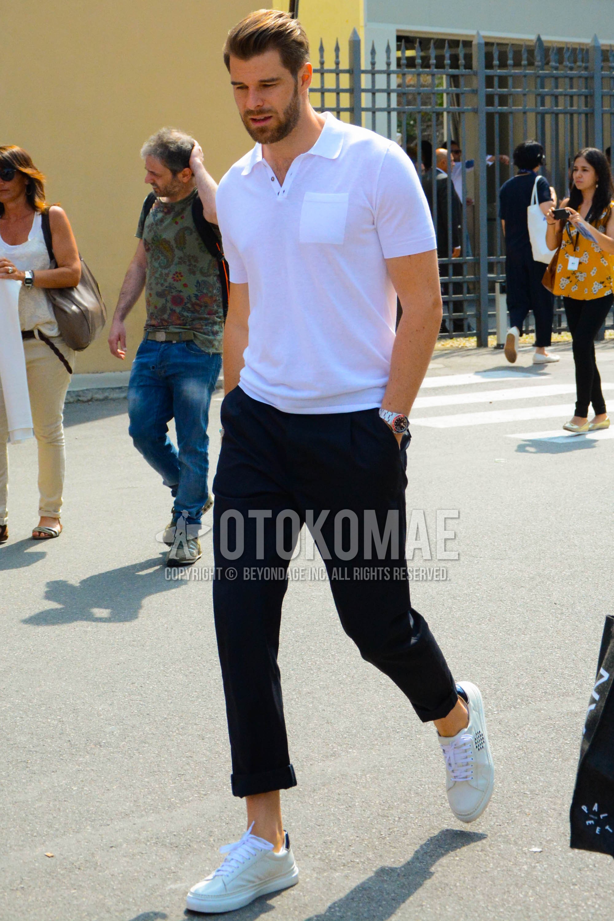 Men's spring summer outfit with white plain polo shirt, navy plain chinos, white low-cut sneakers.