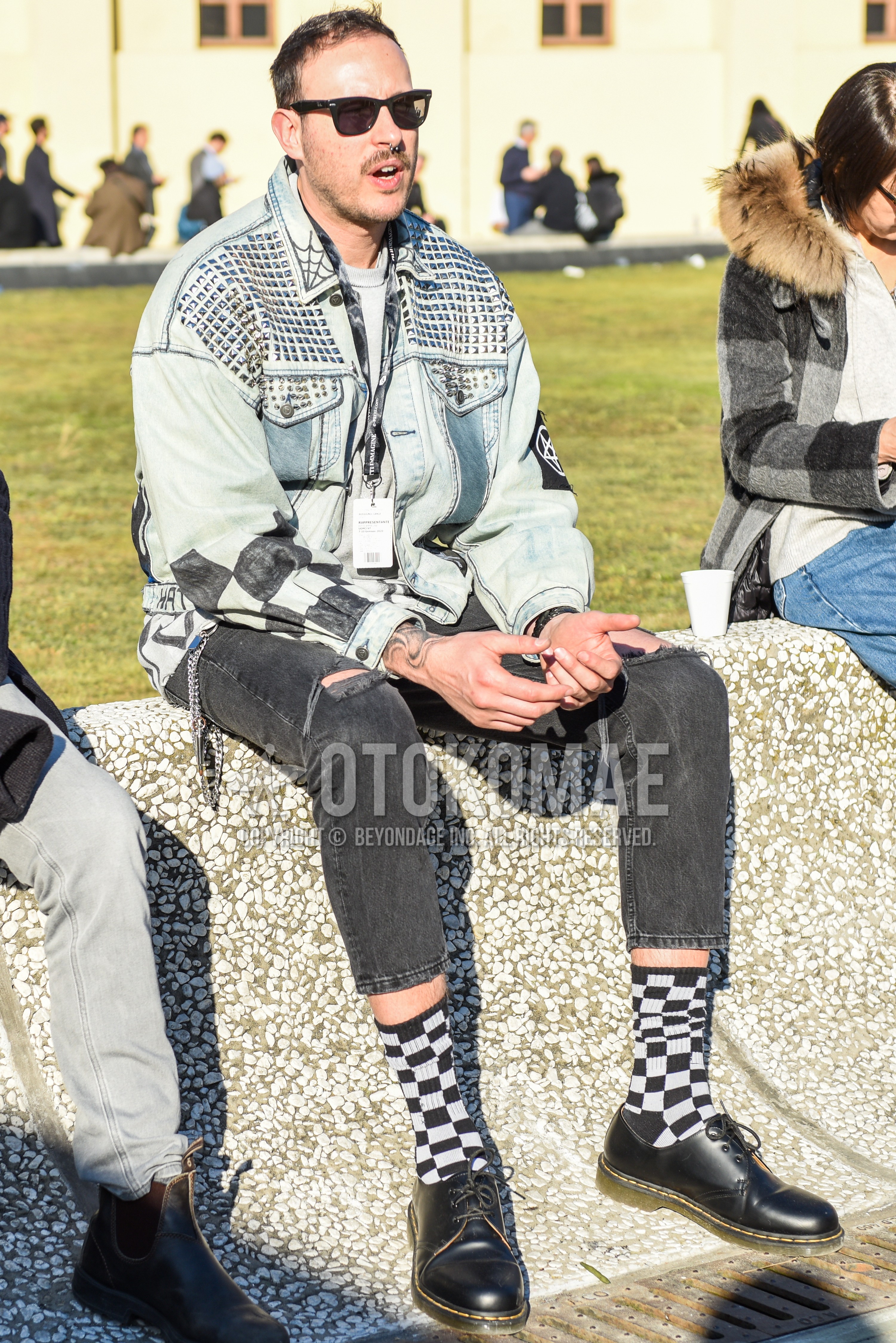 Men's spring autumn outfit with black plain sunglasses, blue plain denim jacket, gray plain t-shirt, dark gray plain damaged jeans, gray black check socks, black plain toe leather shoes.
