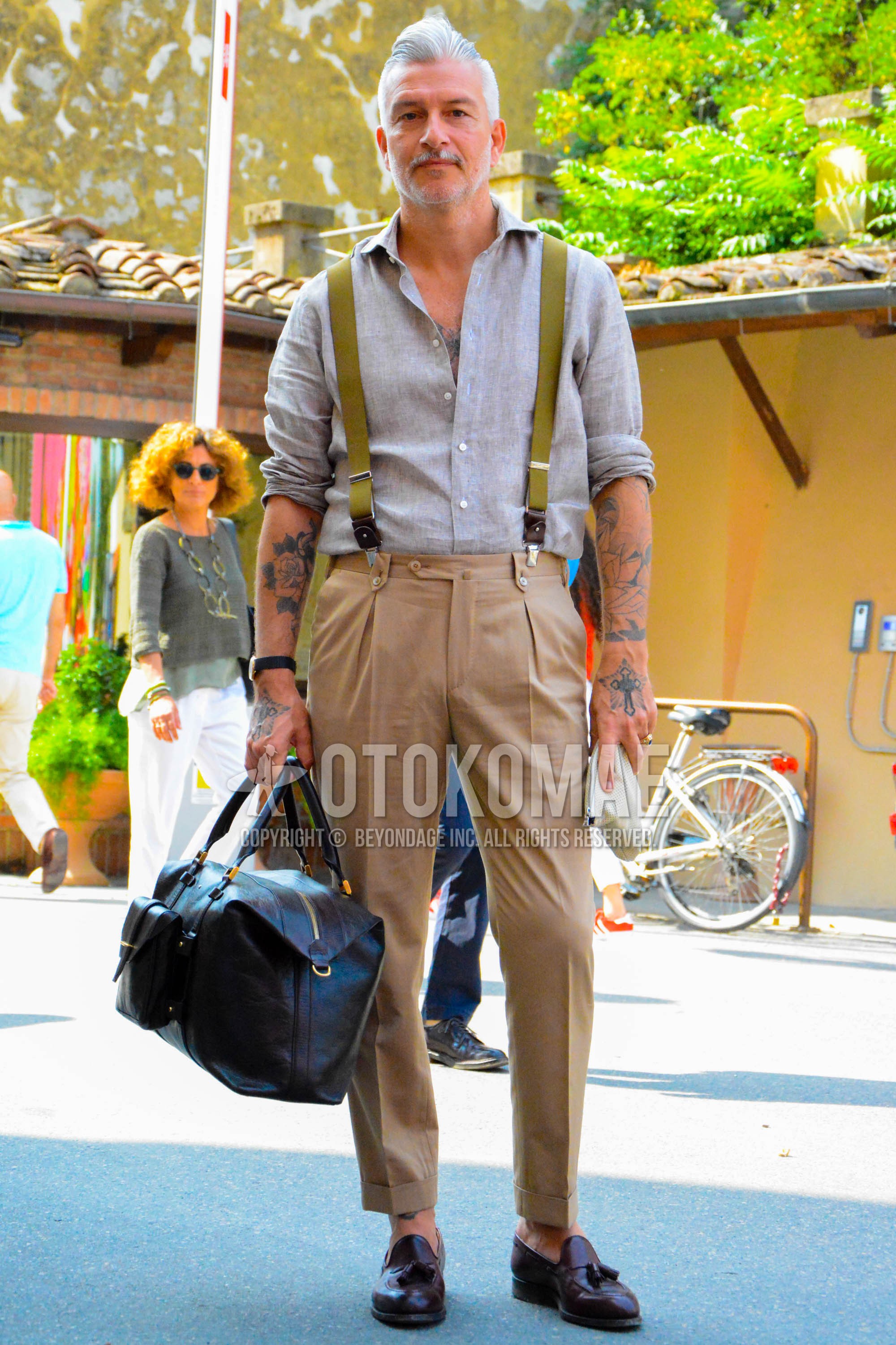 Men's spring summer outfit with gray plain shirt, olive green plain suspenders, beige plain slacks, beige plain pleated pants, beige plain ankle pants, brown tassel loafers leather shoes, brown plain boston bag.