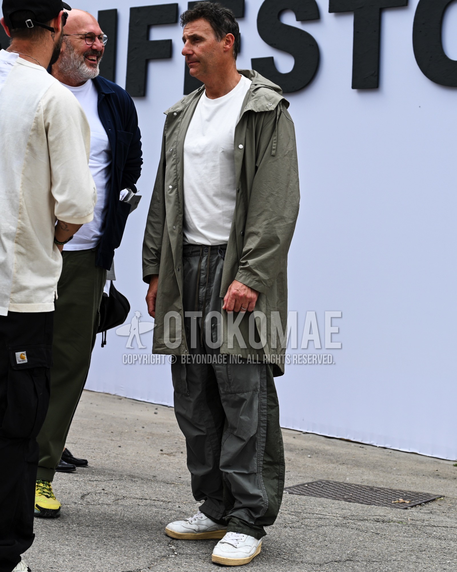 Men's spring autumn outfit with olive green plain hooded coat, white plain t-shirt, olive green plain wide pants, olive green plain cargo pants, white low-cut sneakers.