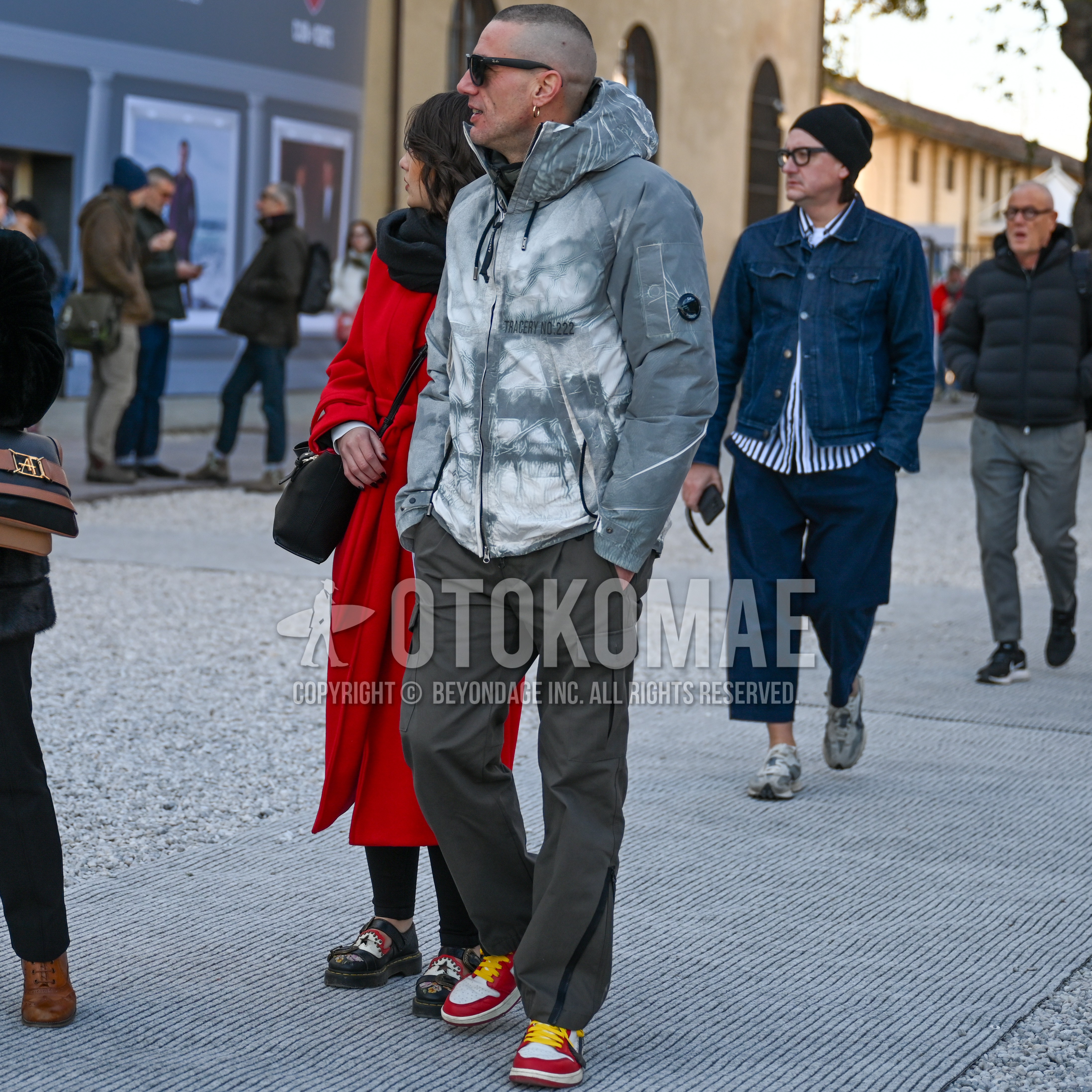 Men's spring autumn winter outfit with black plain sunglasses, gray white outerwear mountain parka, gray plain cargo pants, red yellow white low-cut sneakers.