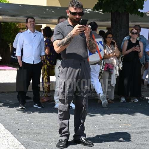 黒無地のサングラス、ニットのグレー無地のポロシャツ、グレー無地のカーゴパンツ、黒ローファーの革靴を合わせた春夏のメンズコーデ・着こなし。