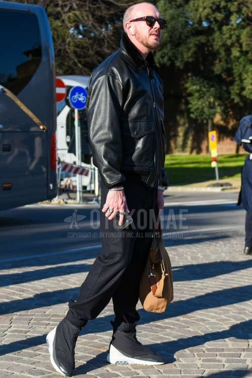 ブラウンべっ甲のサングラス、黒無地のレザージャケット(ライダース以外)、黒無地のミリタリージャケット(MA-1、M-65以外)、ダークグレー無地のスラックス、ナイキ アンブッシュ エアマックス180の黒ハイカットのスニーカー、ベージュ無地のブリーフケース/ハンドバッグを合わせた秋冬のメンズコーデ・着こなし。