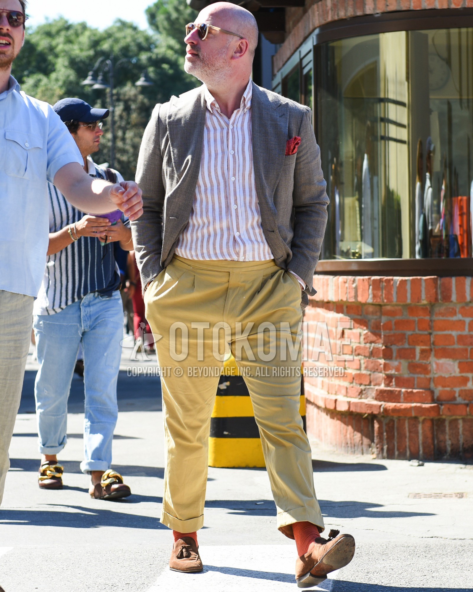 Men's spring summer outfit with beige plain sunglasses, gray check tailored jacket, white brown stripes shirt, yellow plain slacks, orange plain socks, brown tassel loafers leather shoes, brown suede shoes leather shoes.