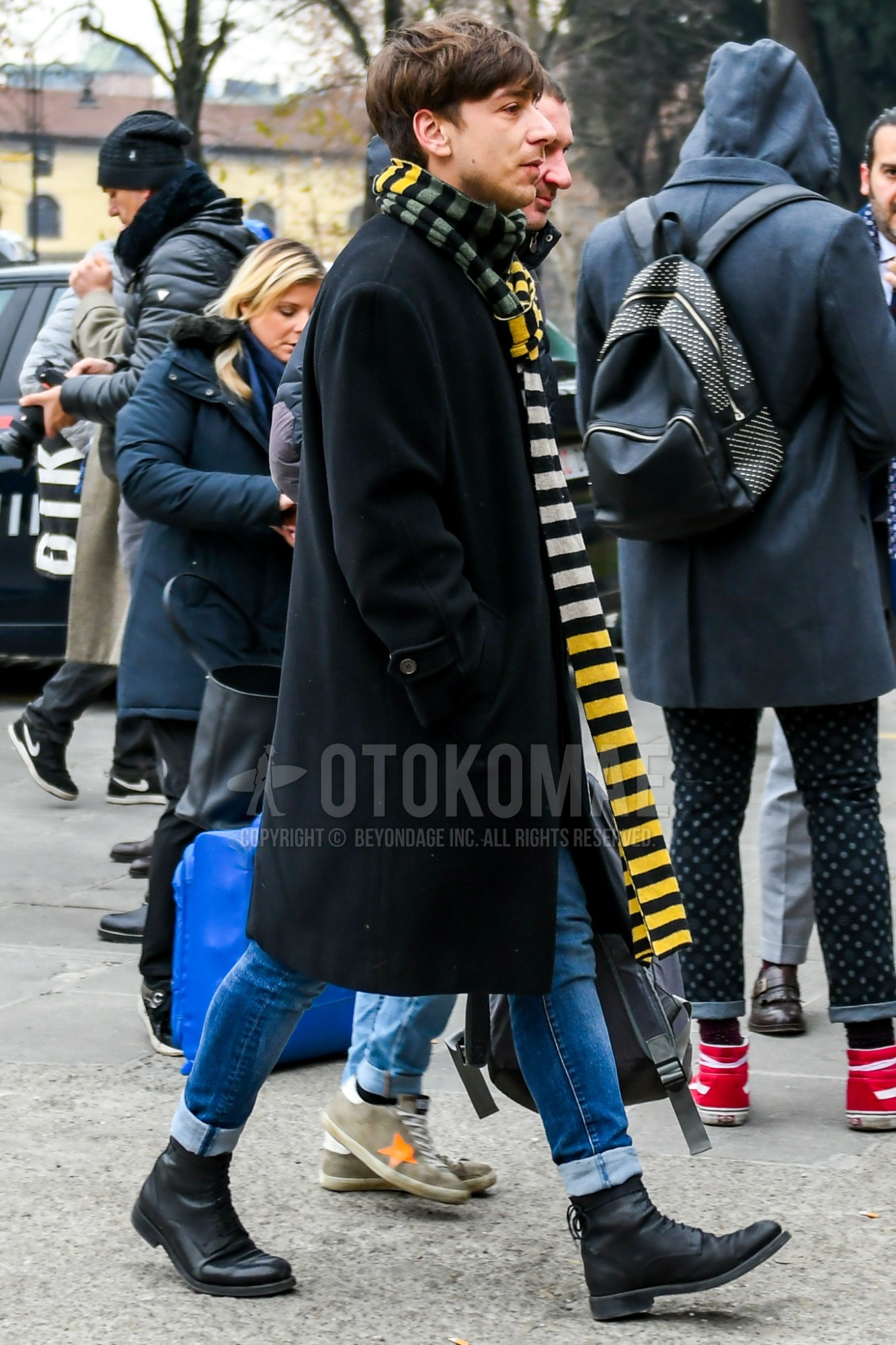 Men's autumn winter outfit with multi-color horizontal stripes scarf, black plain stenkarrer coat, blue plain denim/jeans, black  boots.