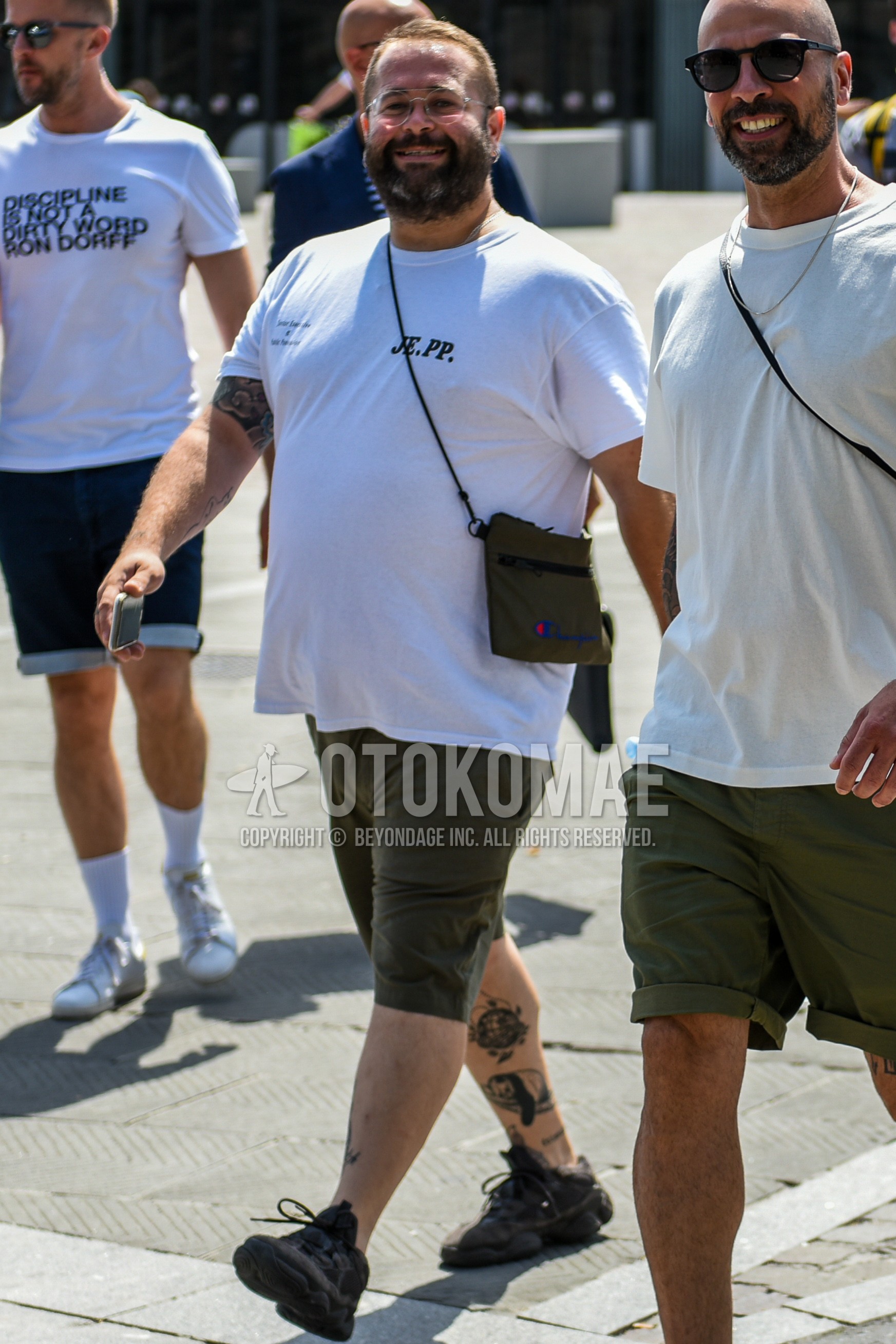 Men's summer outfit with plain glasses, white plain t-shirt, olive green plain short pants, black low-cut sneakers.