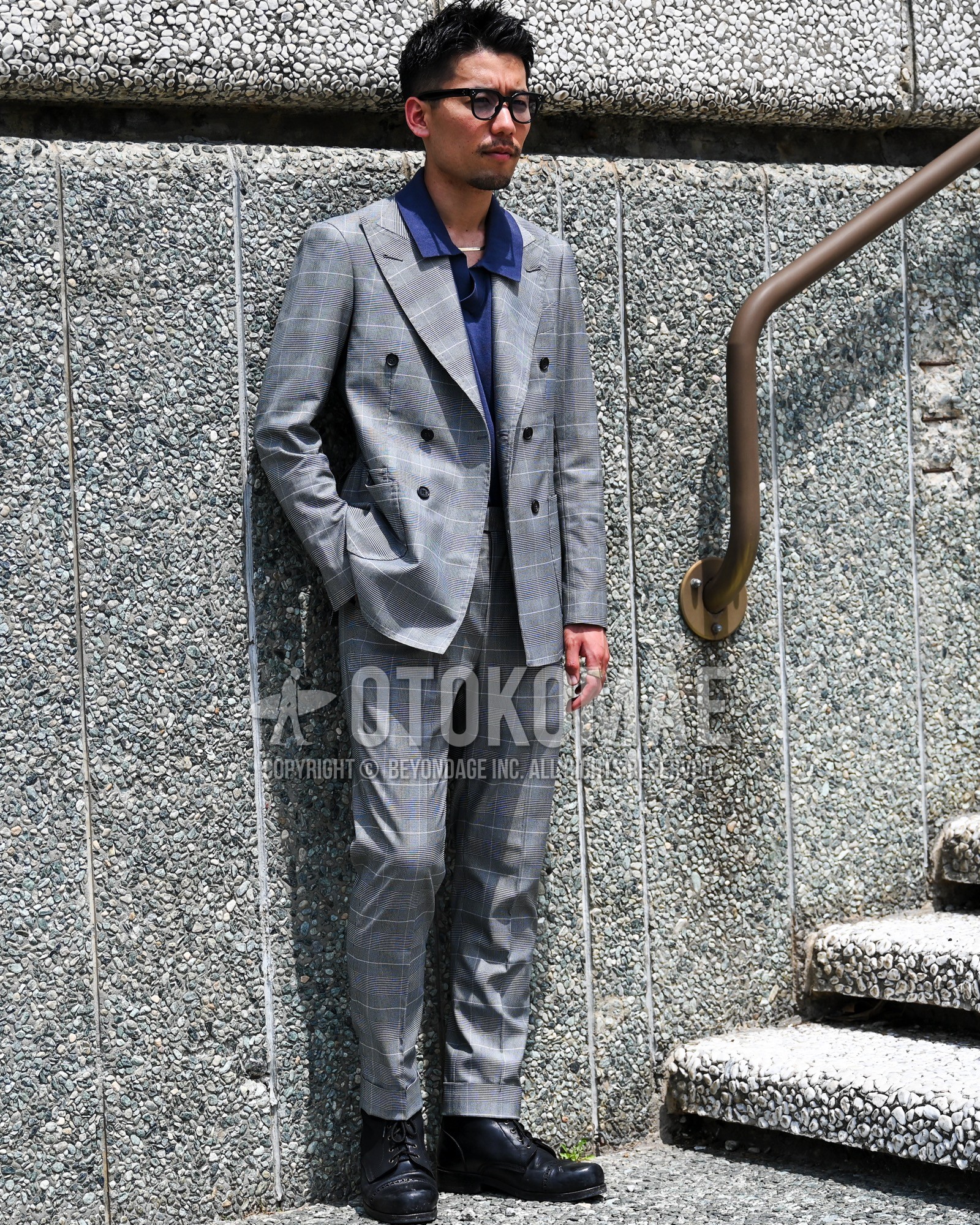 Men's spring summer autumn outfit with clear plain sunglasses, navy plain shirt, black  boots, gray check suit.