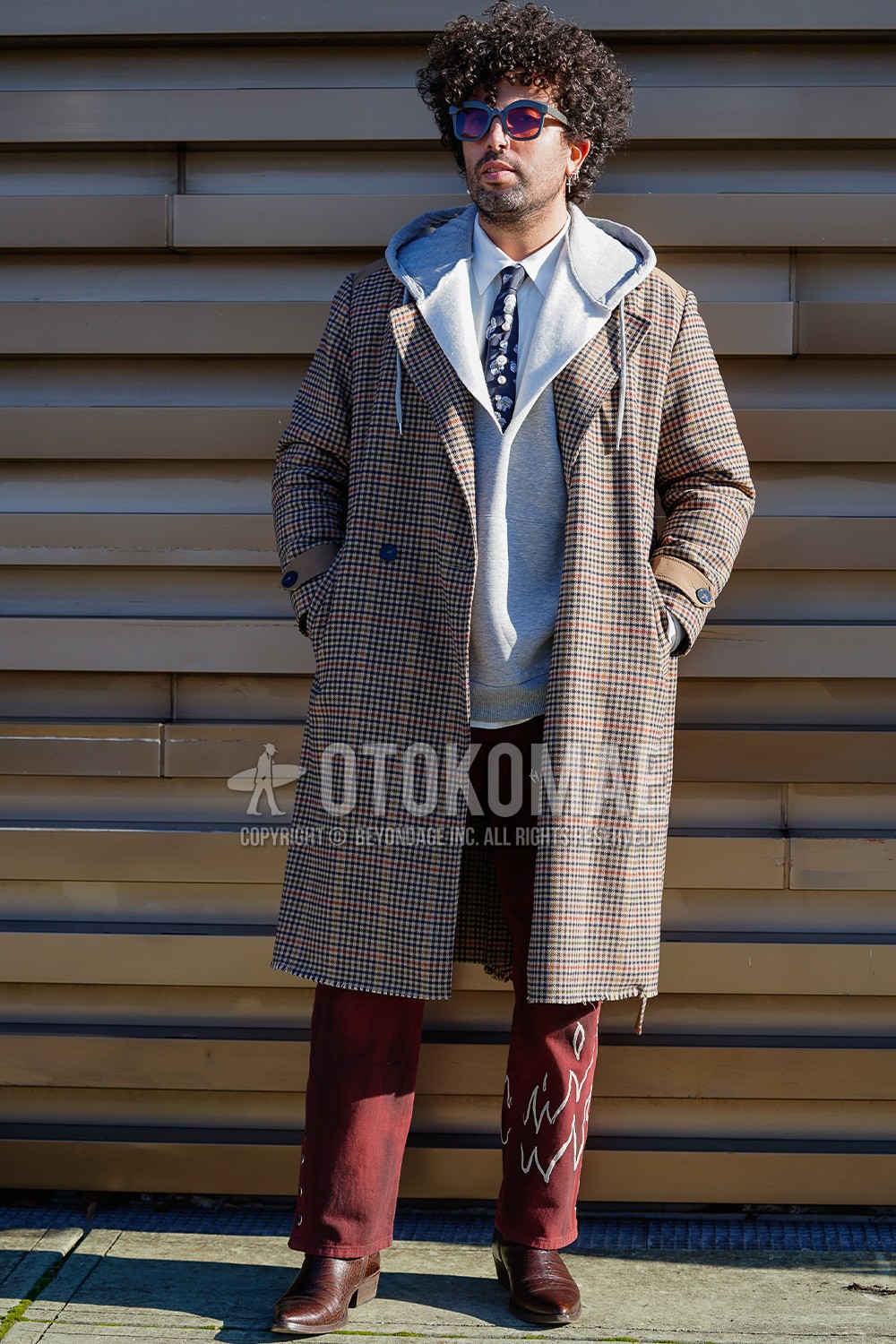 Men's spring winter outfit with black plain sunglasses, brown check trench coat, brown check chester coat, gray plain hoodie, white plain shirt, red graphic denim/jeans, red graphic slacks, red  boots, black necktie necktie.