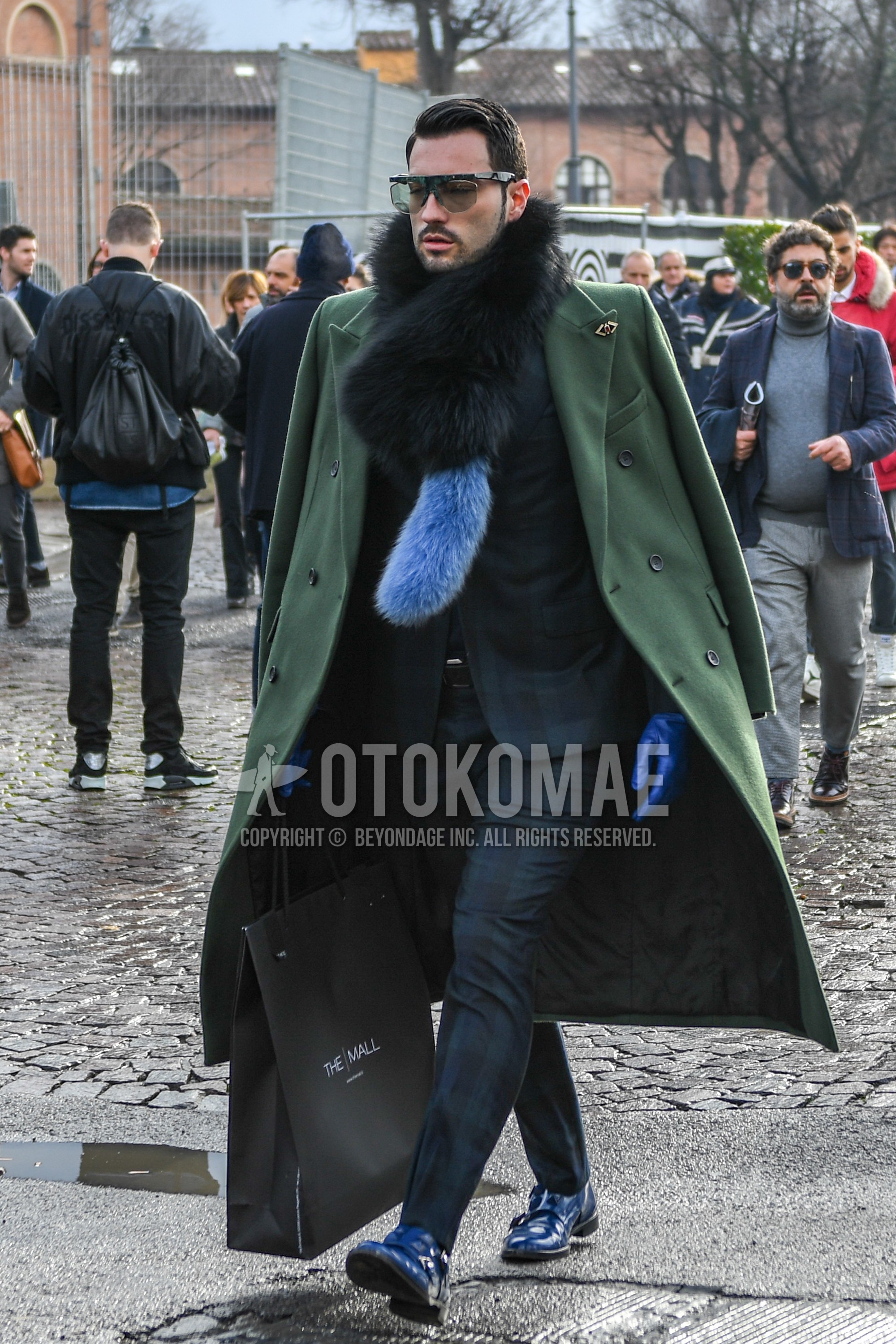 Men's winter outfit with black plain sunglasses, black plain scarf, green plain chester coat, black plain leather belt, blue monk shoes leather shoes, green check suit.