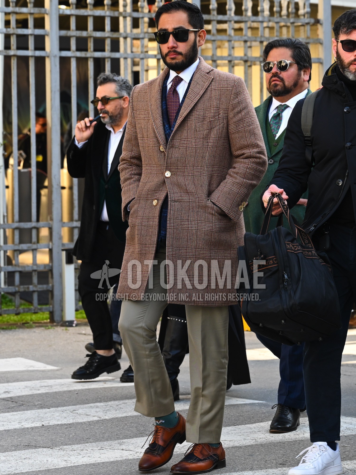 Men's autumn winter outfit with black plain sunglasses, brown check chester coat, white plain shirt, navy check tailored jacket, olive green plain slacks, green one point socks, brown brogue shoes leather shoes, red check necktie.