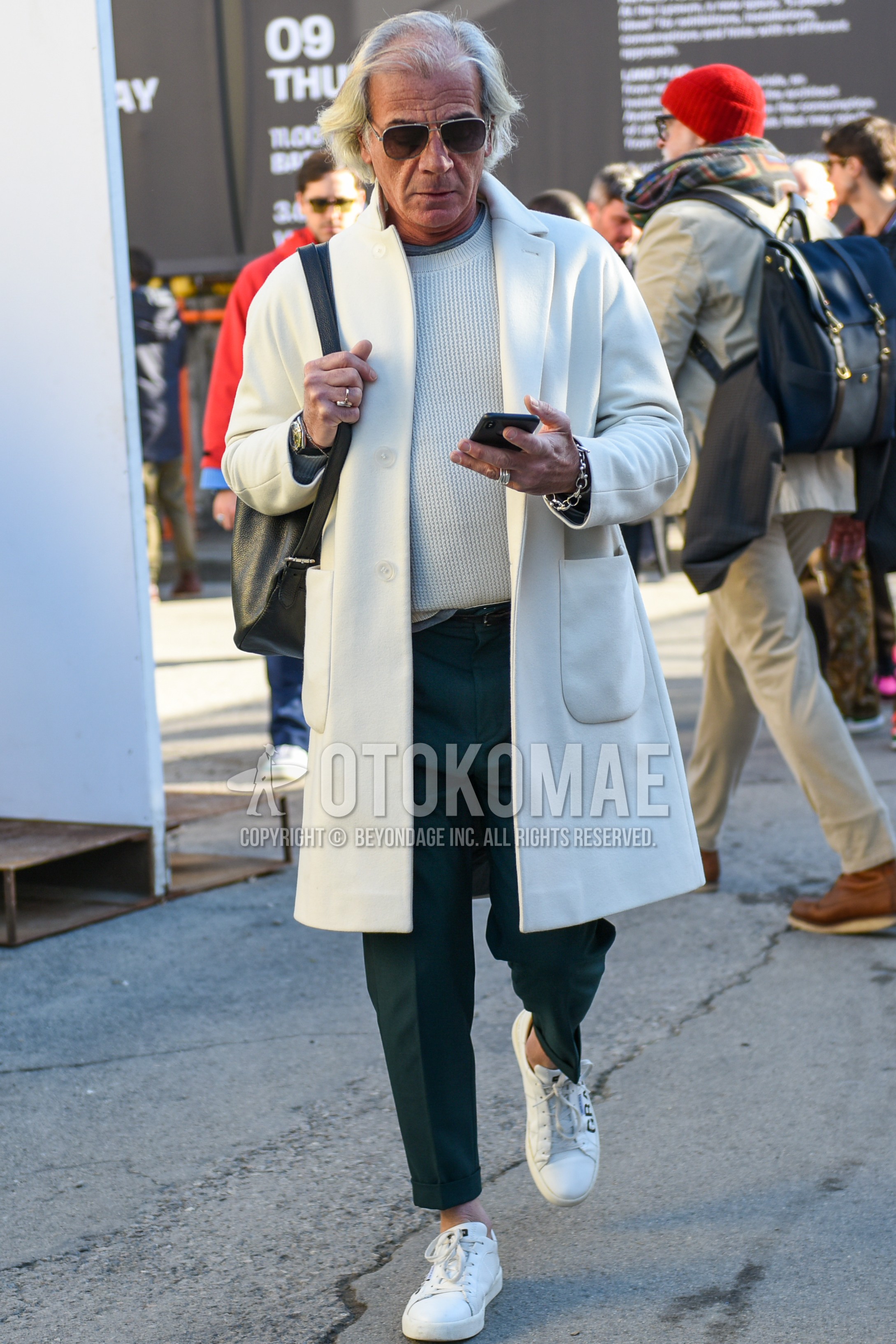 Men's autumn winter outfit with silver plain sunglasses, white plain chester coat, white plain sweater, gray plain slacks, gray plain cropped pants, white low-cut sneakers, black plain backpack.