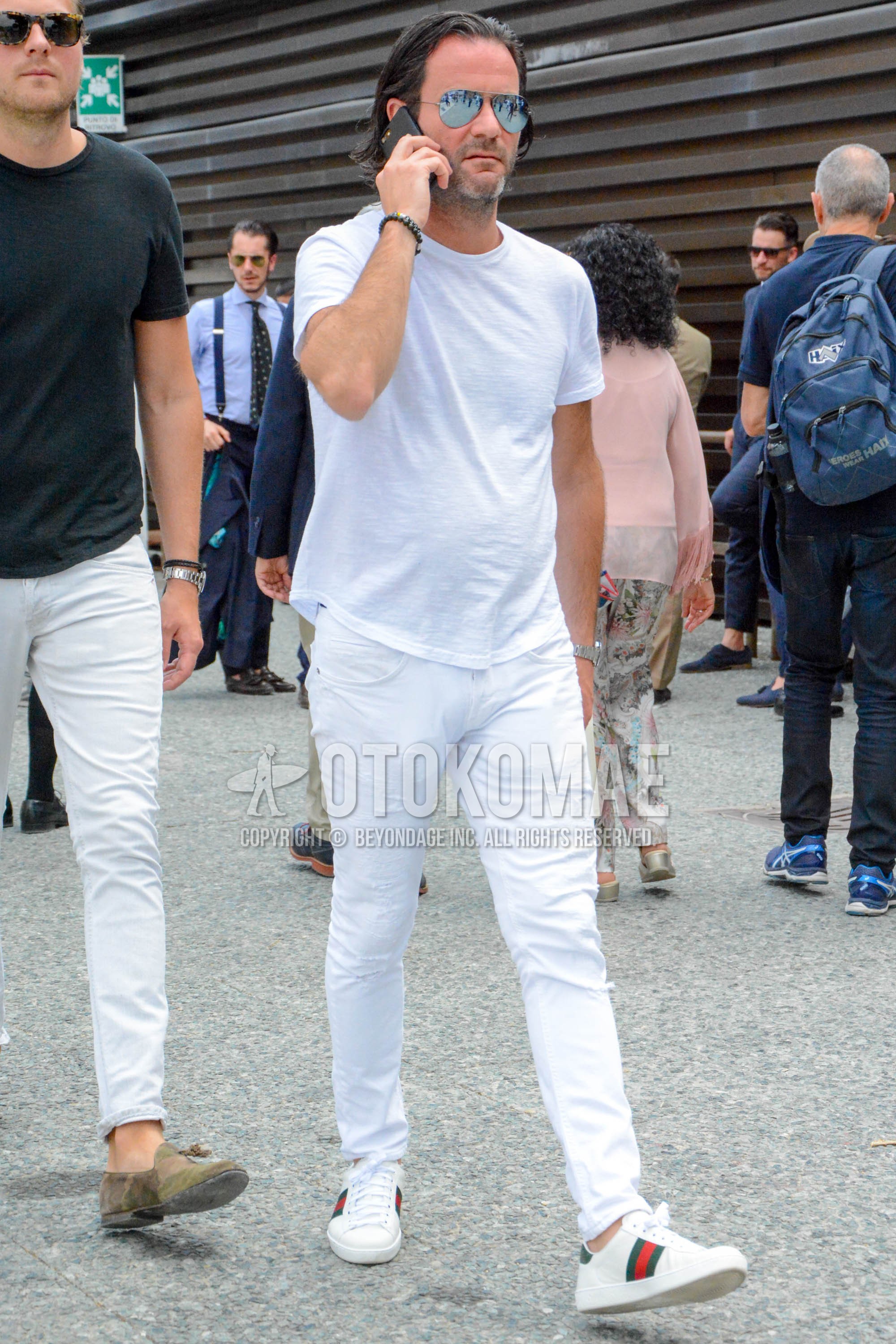 Men's spring summer outfit with silver plain sunglasses, white plain t-shirt, white plain damaged jeans, white low-cut sneakers.