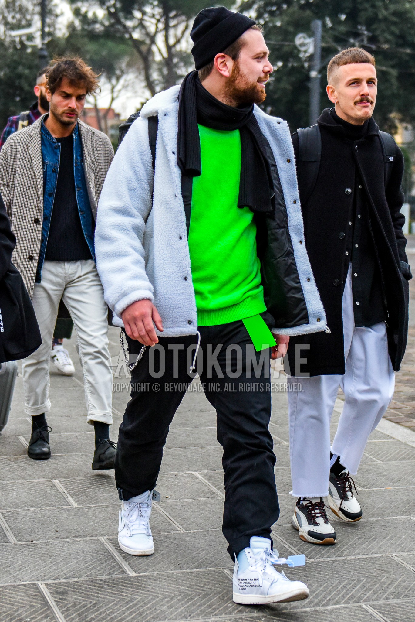 Men's winter outfit with black plain knit cap, black plain scarf, white plain coach jacket, green plain sweater, green plain tape belt, black plain cotton pants, white high-cut sneakers.