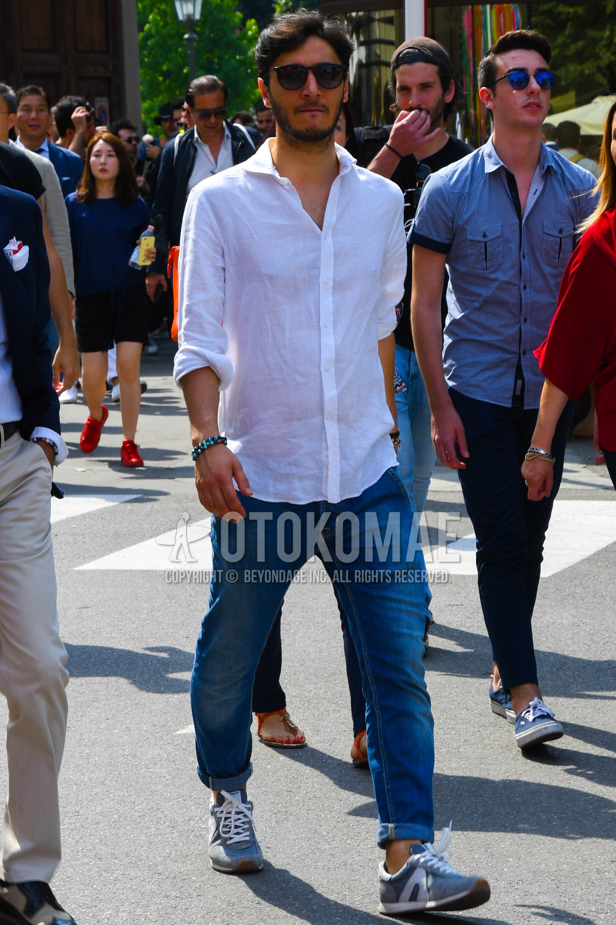 Men's spring summer outfit with black plain sunglasses, white plain shirt, blue plain denim/jeans, gray low-cut sneakers.