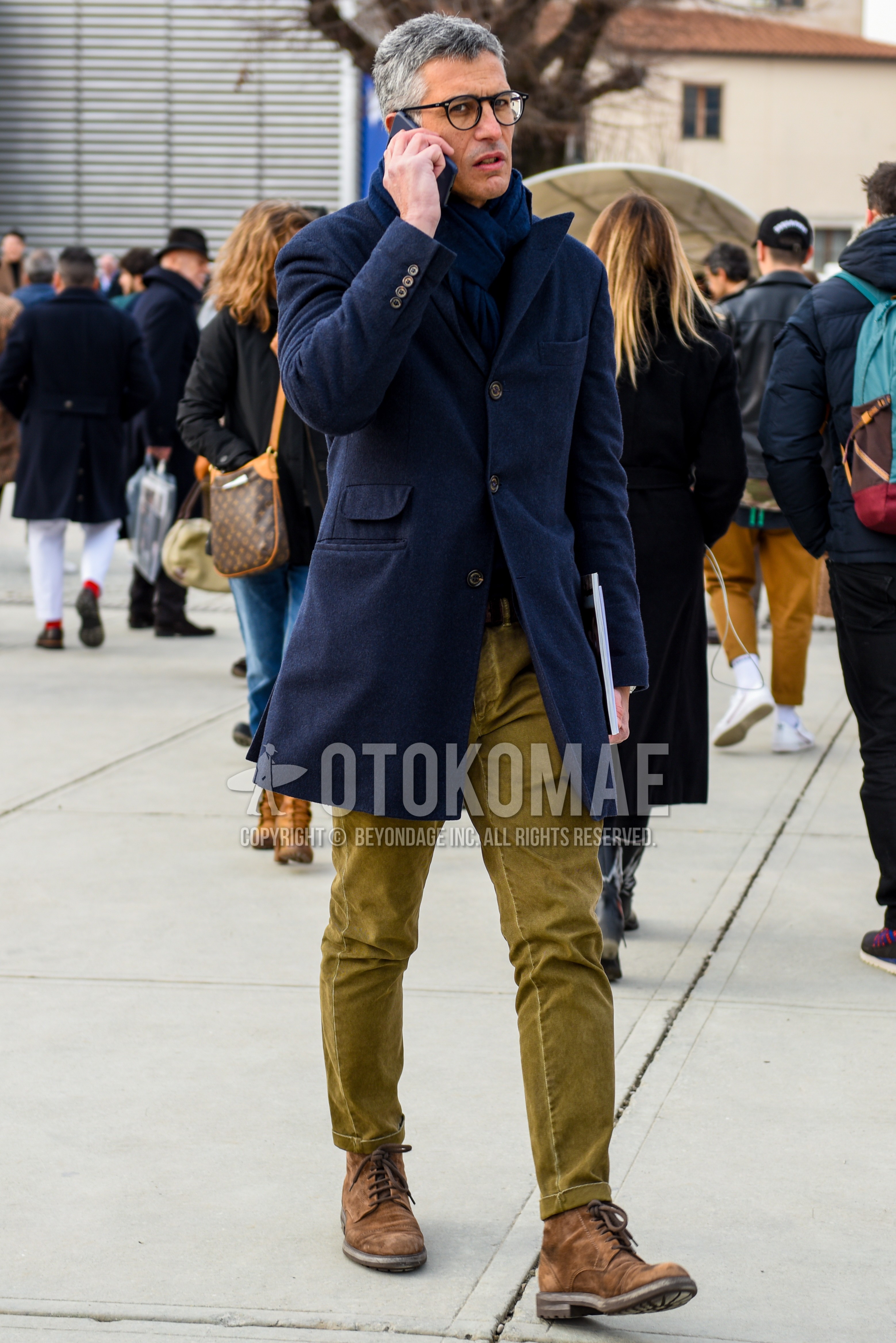 Men's autumn winter outfit with black plain glasses, navy plain scarf, navy plain chester coat, olive green plain slacks, brown  boots.