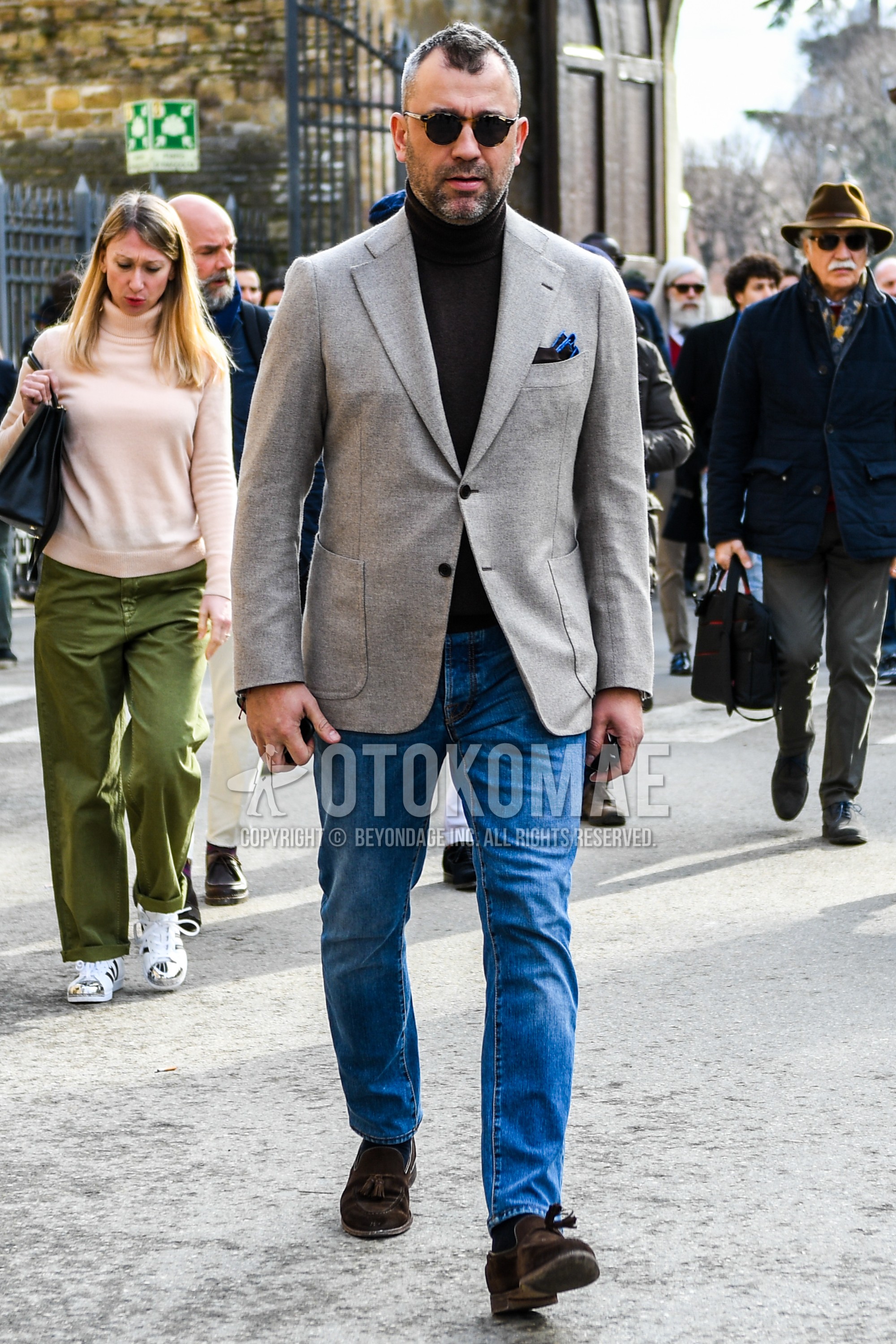 Men's winter outfit with plain sunglasses, gray plain tailored jacket, brown plain turtleneck knit, blue plain denim/jeans, brown tassel loafers leather shoes.