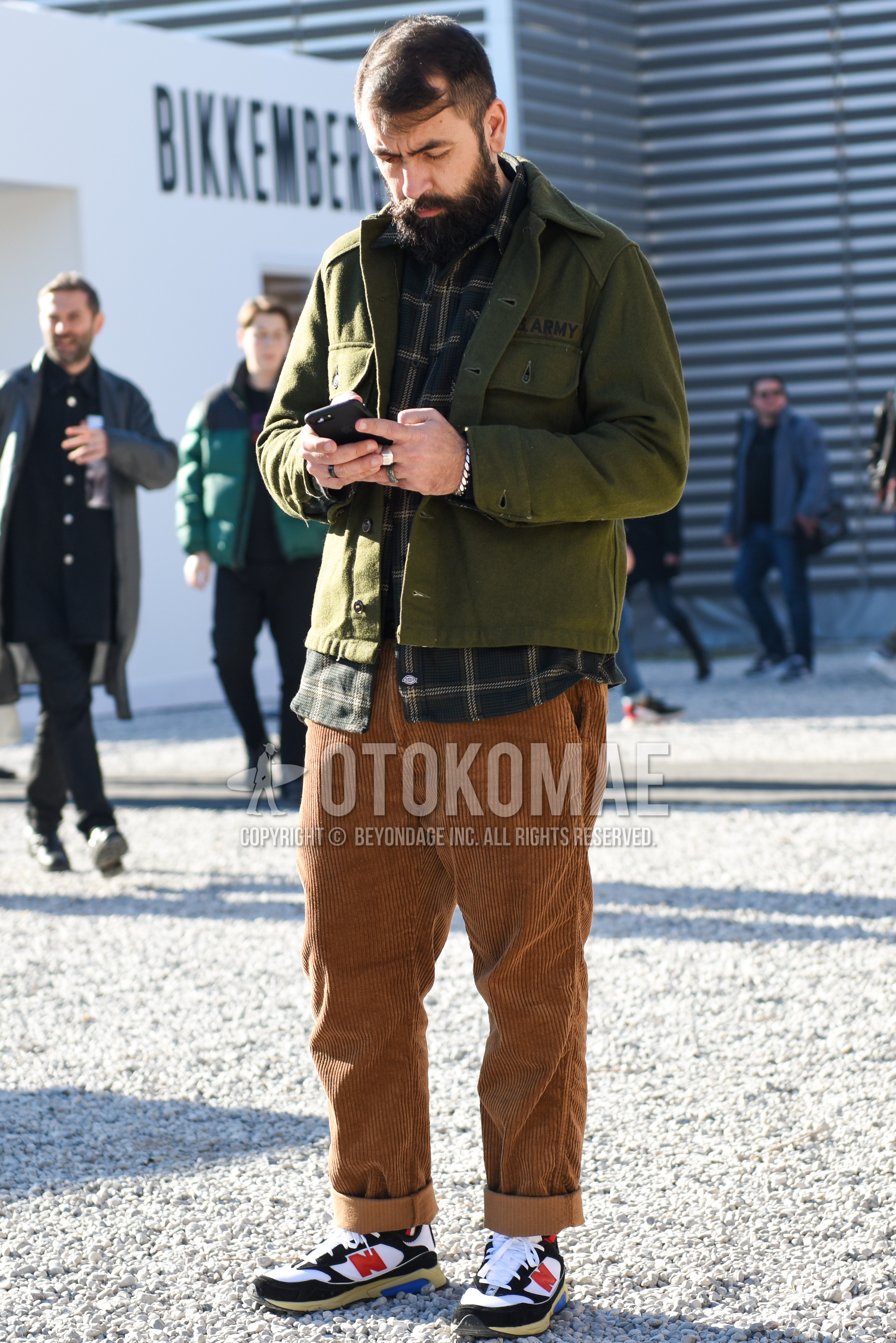 Men's autumn winter outfit with olive green plain shirt jacket, dark gray check shirt, brown plain winter pants (corduroy,velour), white black low-cut sneakers.