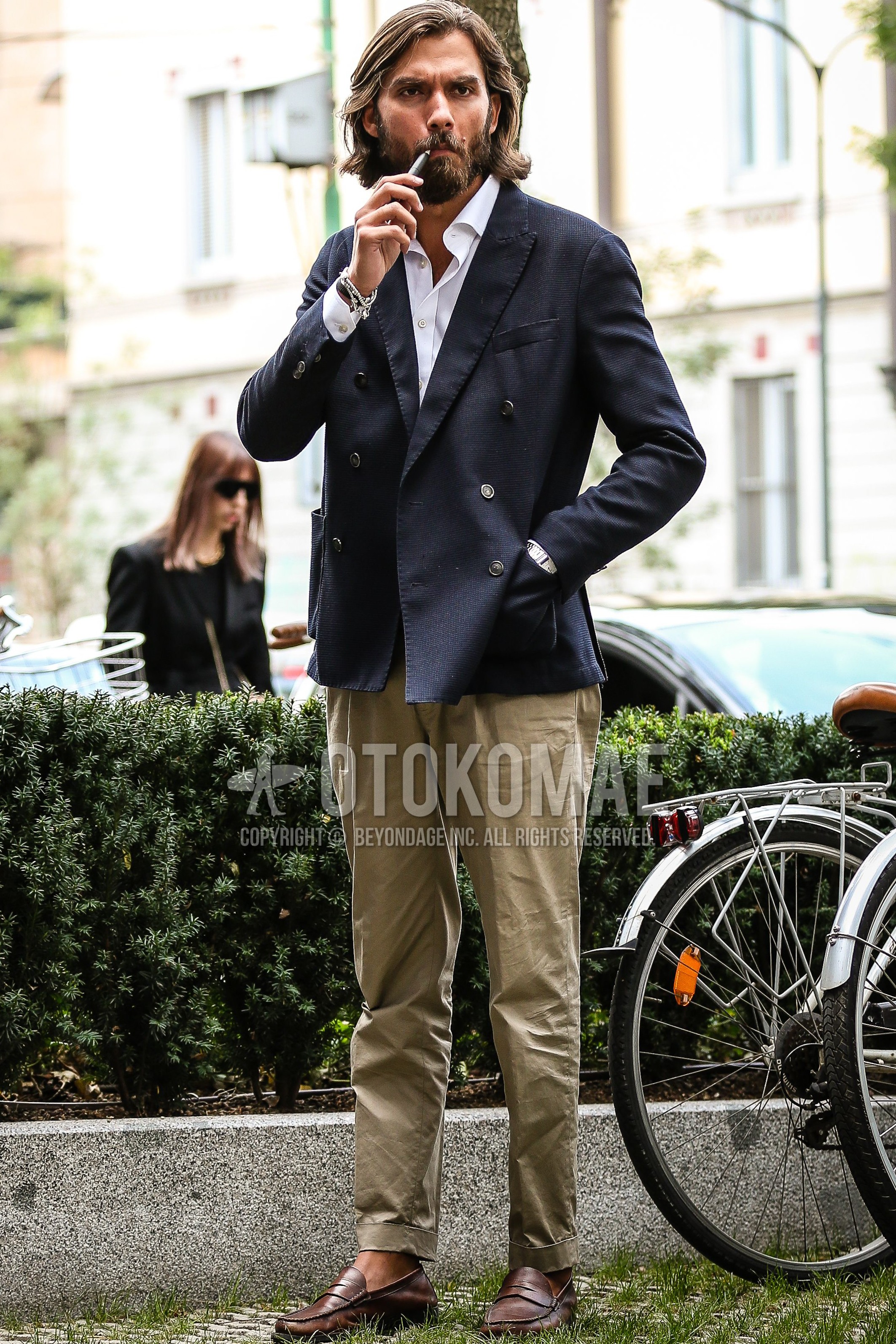 Men's spring outfit with navy plain tailored jacket, white plain shirt, olive green beige plain chinos, brown coin loafers leather shoes.
