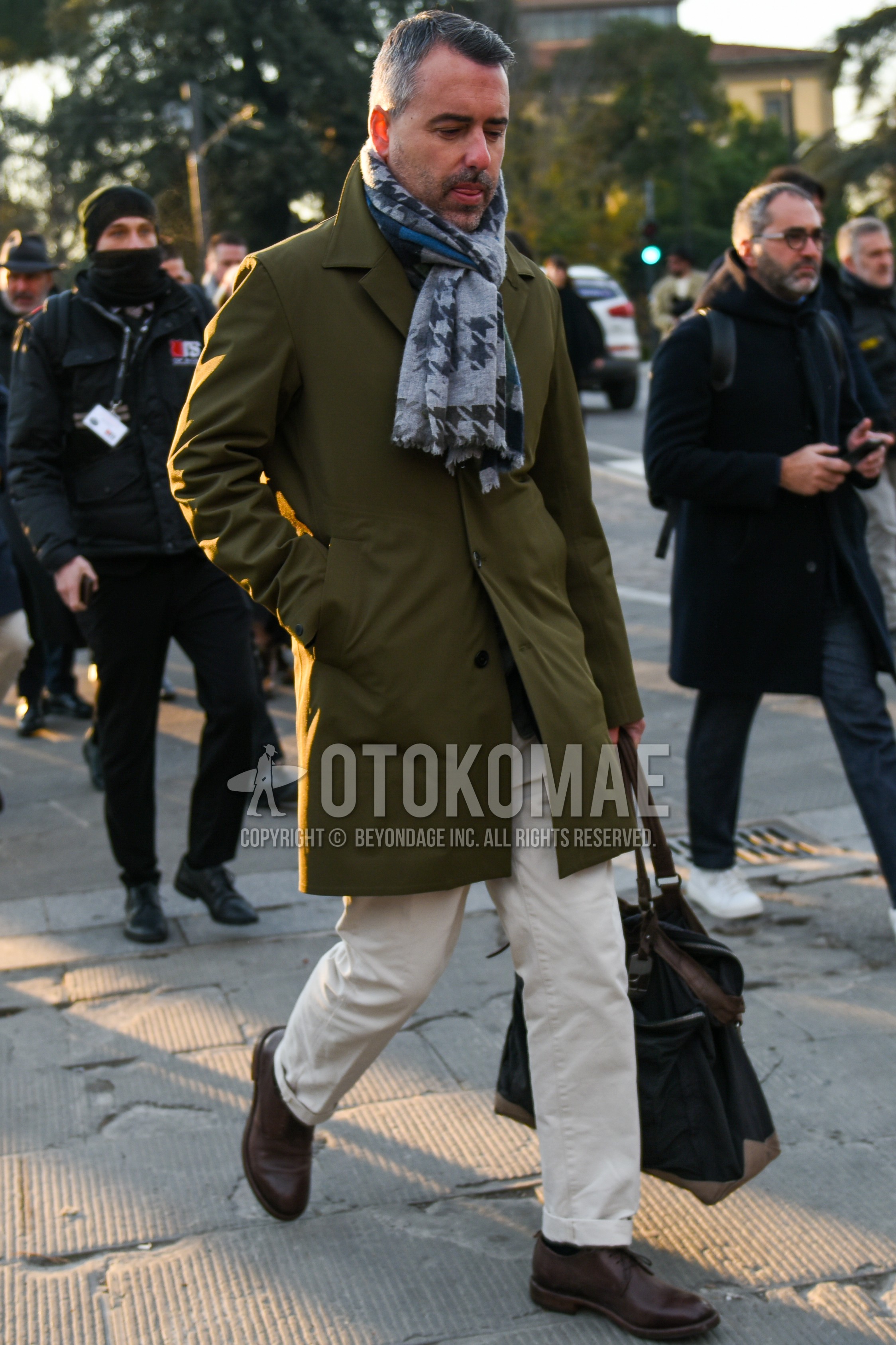 Men's autumn winter outfit with gray scarf scarf, olive green plain stenkarrer coat, white plain cotton pants, brown plain toe leather shoes, navy plain briefcase/handbag.