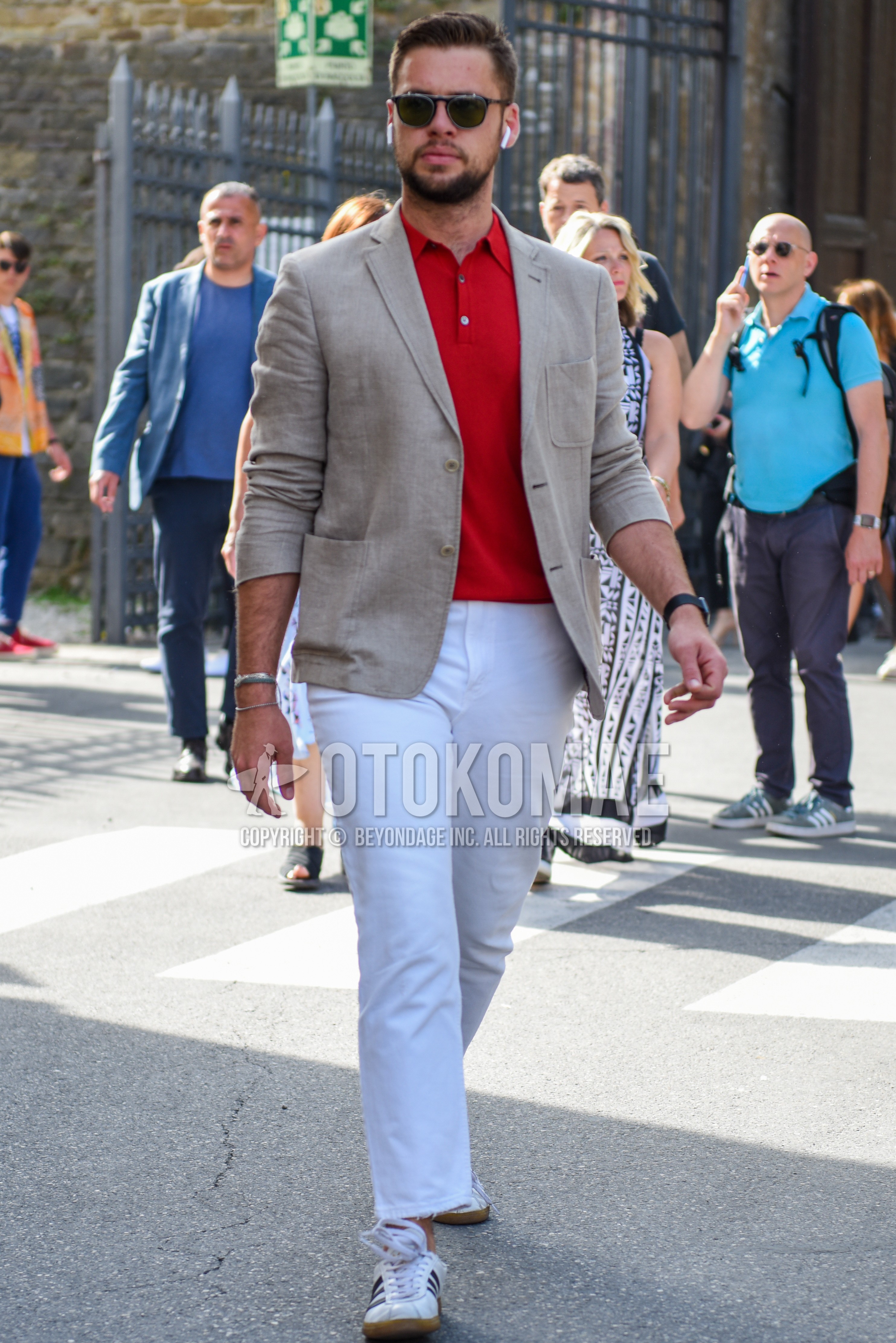 Men's spring summer autumn outfit with black plain sunglasses, beige plain tailored jacket, red plain polo shirt, white cotton pants, white low-cut sneakers.