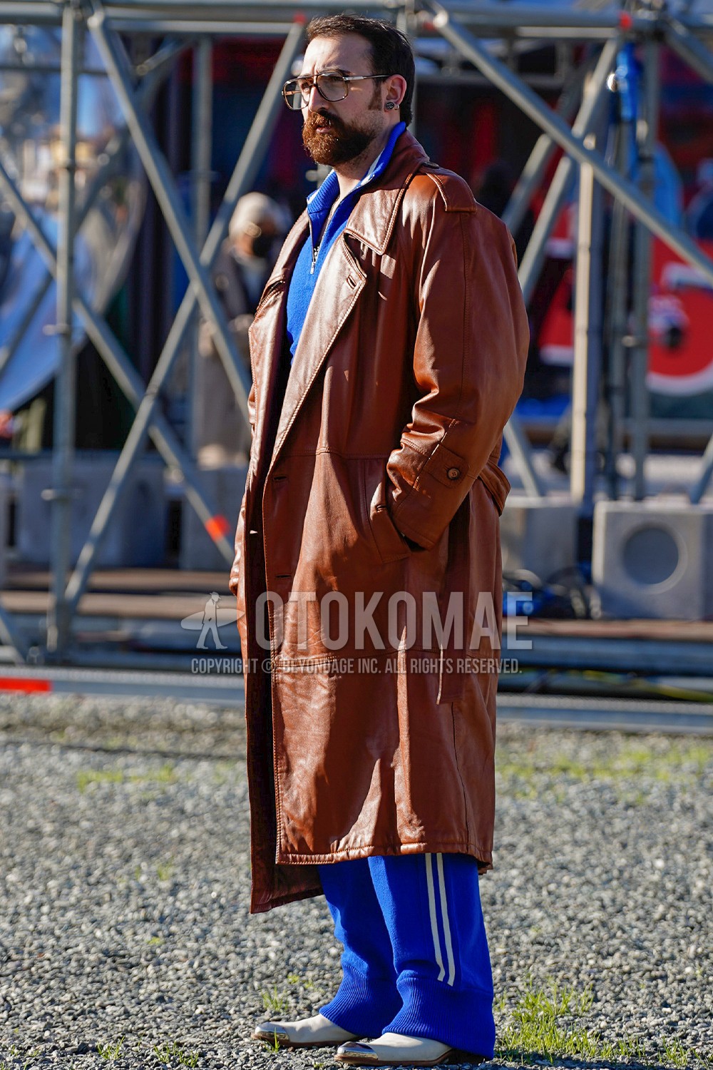 Men's spring winter outfit with brown plain glasses, orange brown plain trench coat, white  boots, blue plain casual setup.