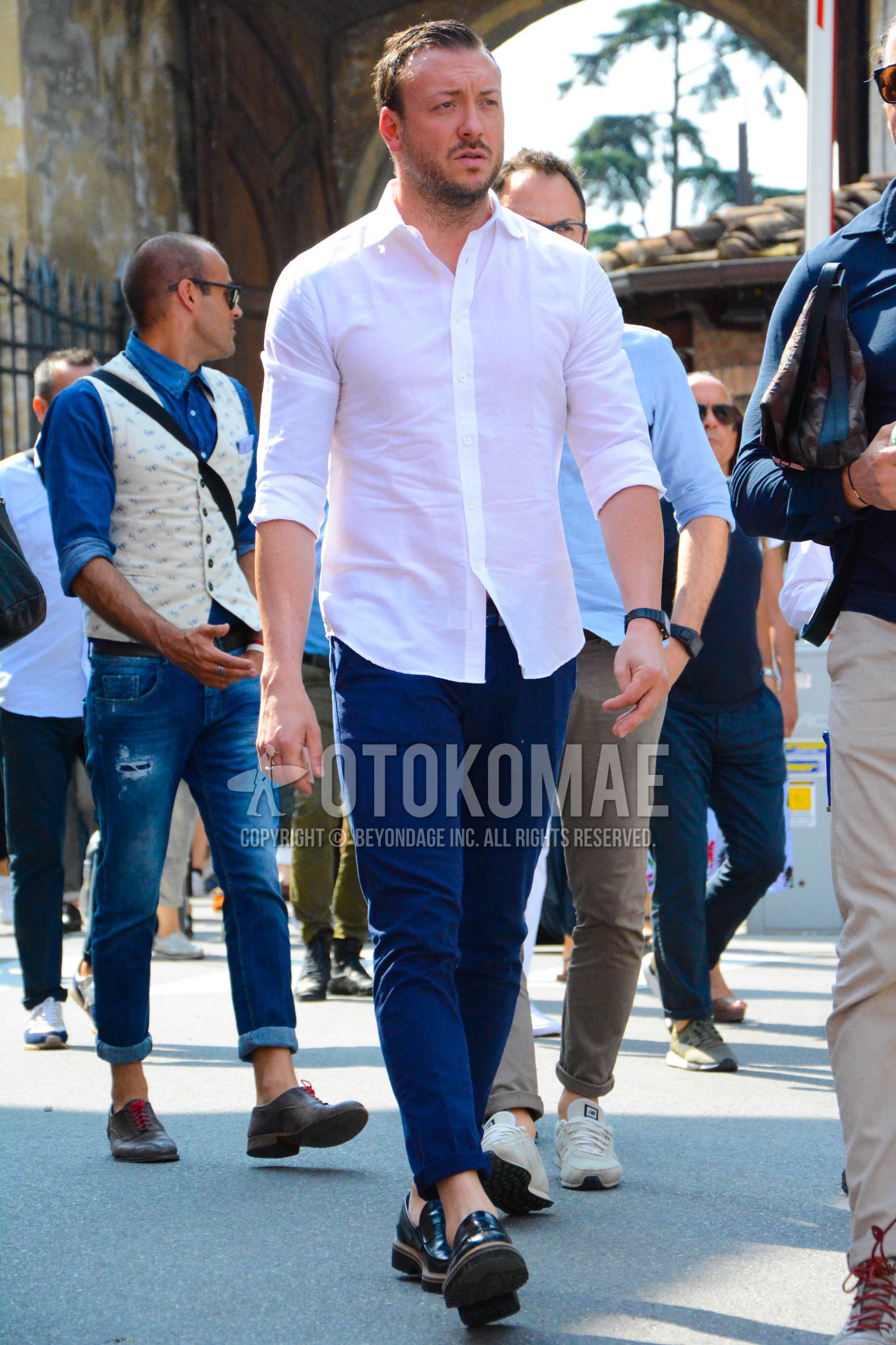 Men's spring summer outfit with white plain shirt, navy plain chinos, black coin loafers leather shoes.