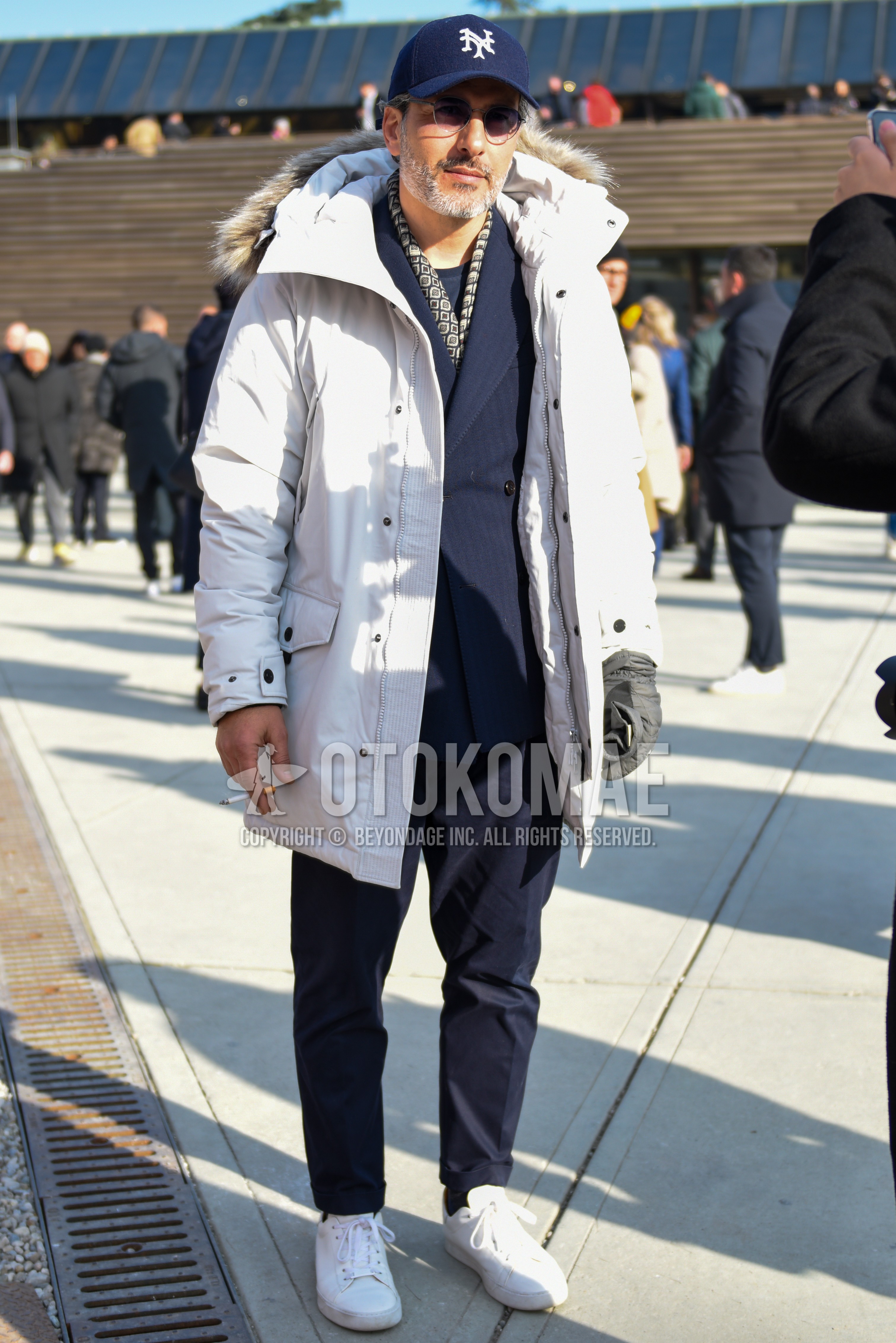 Men's winter outfit with navy cap baseball cap, silver plain sunglasses, multi-color scarf scarf, white plain down jacket, white low-cut sneakers, navy stripes suit.