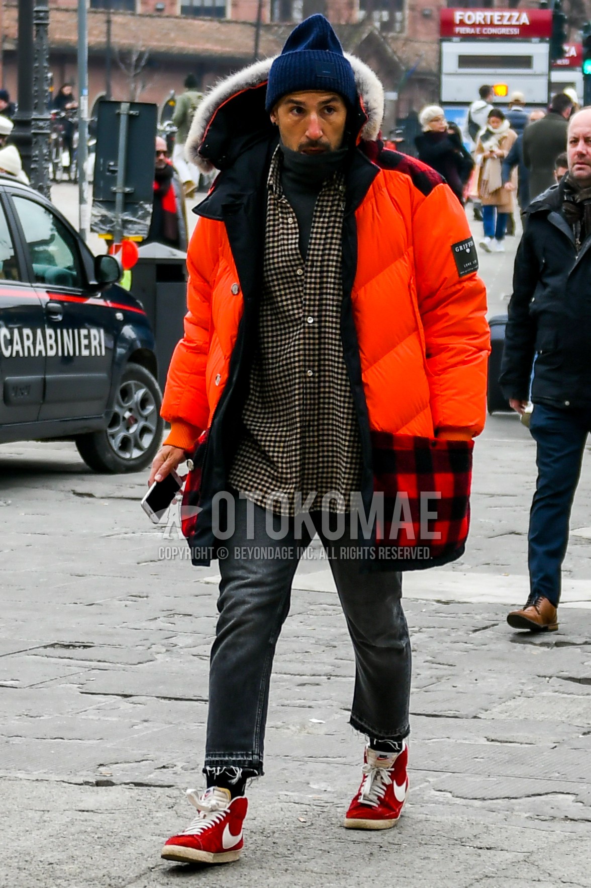 Men's winter outfit with navy plain knit cap, orange plain down jacket, black beige check shirt, gray plain turtleneck knit, gray plain denim/jeans, black plain socks, red high-cut sneakers.