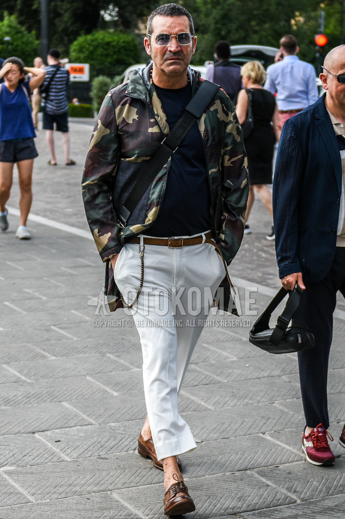 Men's spring autumn outfit with silver plain sunglasses, olive green camouflage hooded coat, navy plain t-shirt, brown plain leather belt, white plain cotton pants, brown wing-tip shoes leather shoes.