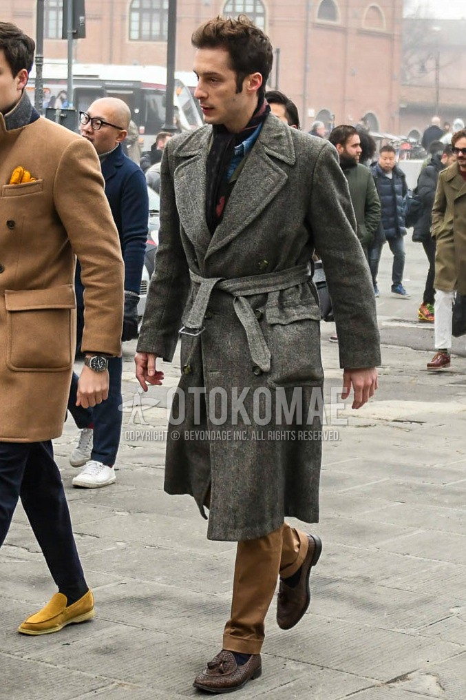 Men's winter outfit with multi-color scarf scarf, gray plain belted coat, brown plain chinos, black plain socks, brown tassel loafers leather shoes.