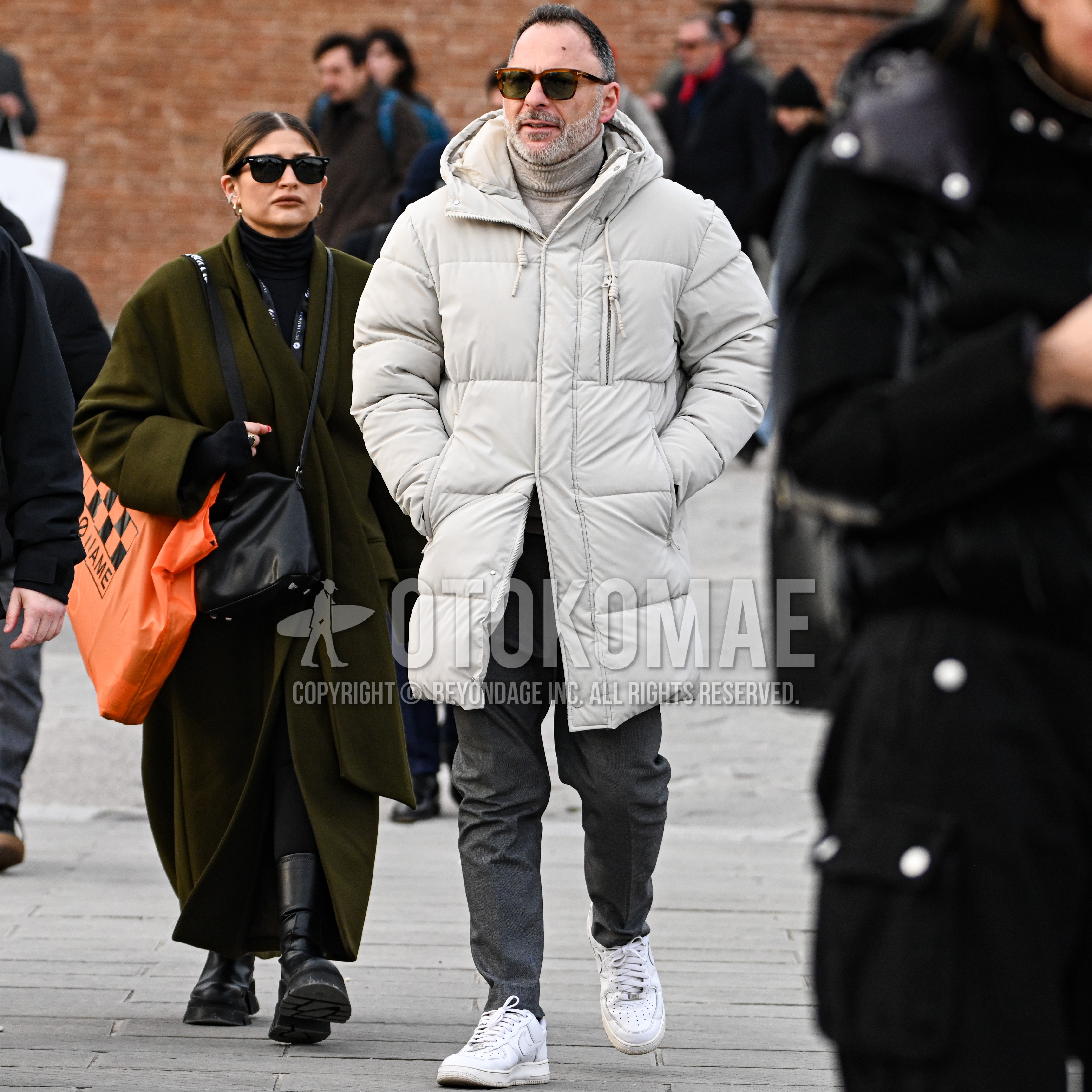 Men's autumn winter outfit with brown tortoiseshell sunglasses, beige plain hooded coat, beige plain turtleneck knit, dark gray plain slacks, white low-cut sneakers.