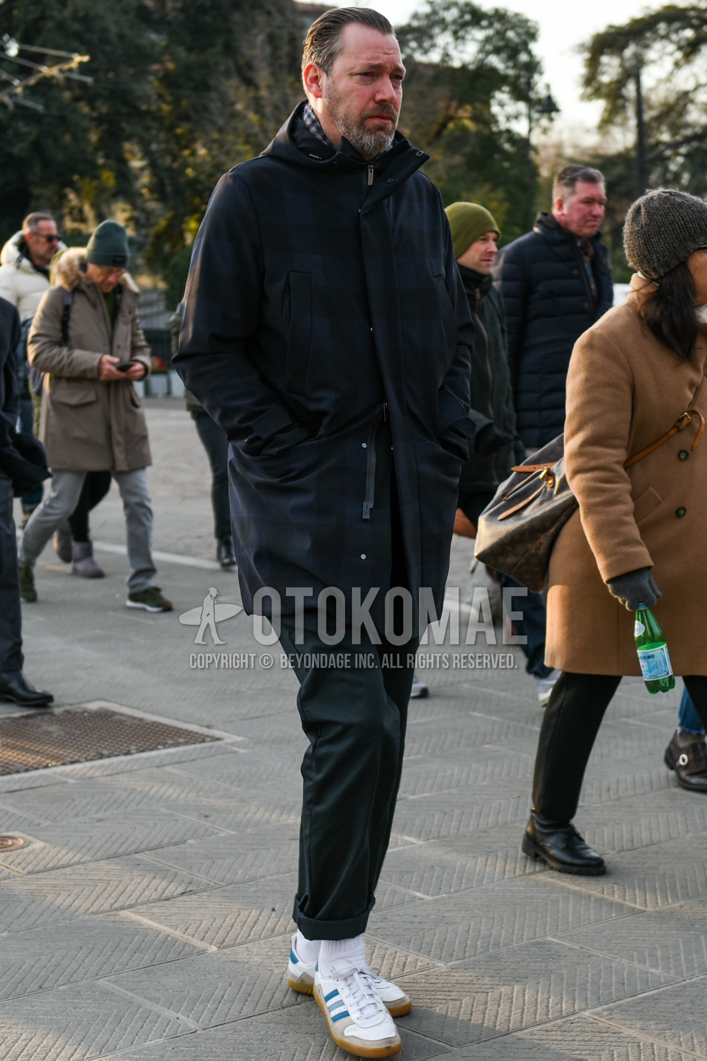 Men's autumn winter outfit with navy check hooded coat, gray plain slacks, white plain socks, white low-cut sneakers.