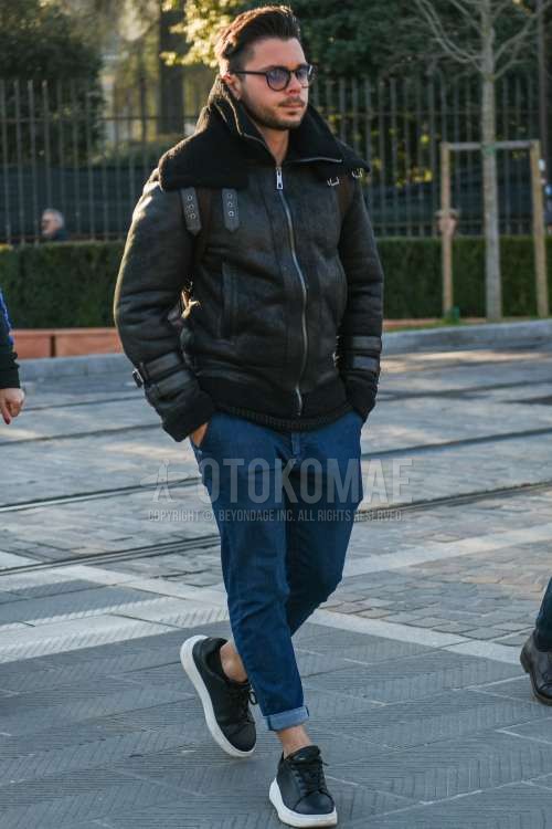 黒無地のサングラス、黒無地のレザージャケット(ライダース以外)、黒無地のミリタリージャケット(MA-1、M-65以外)、ブルー無地のデニム/ジーンズ、アレキサンダーマックィーンの黒ローカットのスニーカーを合わせた秋冬のメンズコーデ・着こなし。