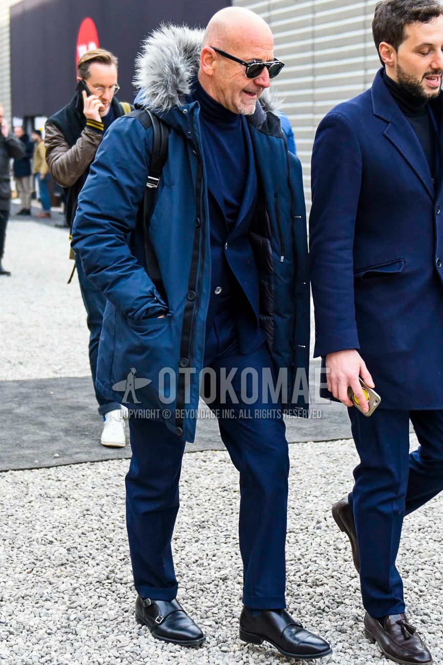 Men's winter outfit with plain sunglasses, blue plain down jacket, blue plain turtleneck knit, black monk shoes leather shoes, blue plain suit.