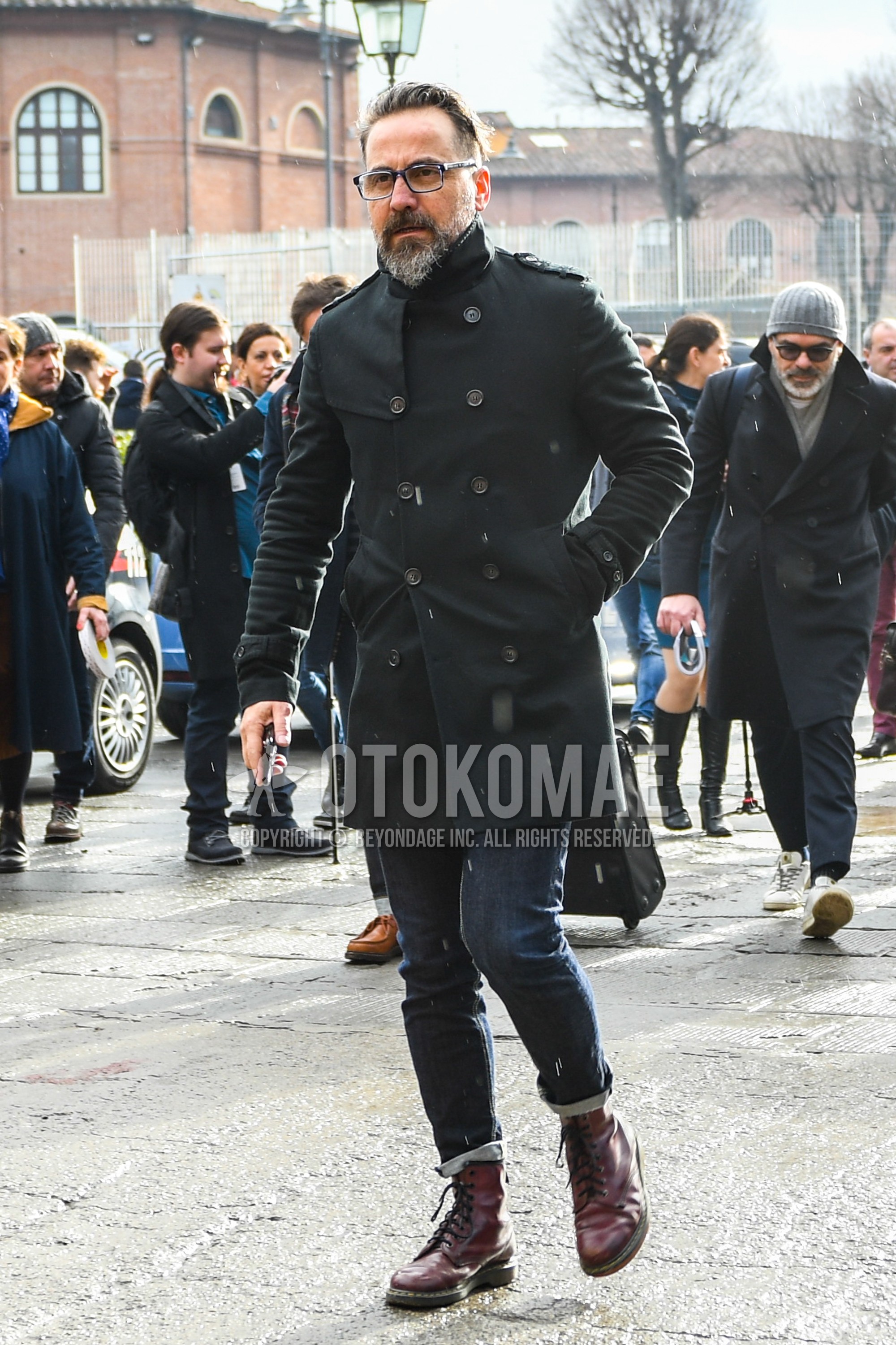 Men's winter outfit with black plain glasses, black plain trench coat, navy plain denim/jeans, brown  boots.