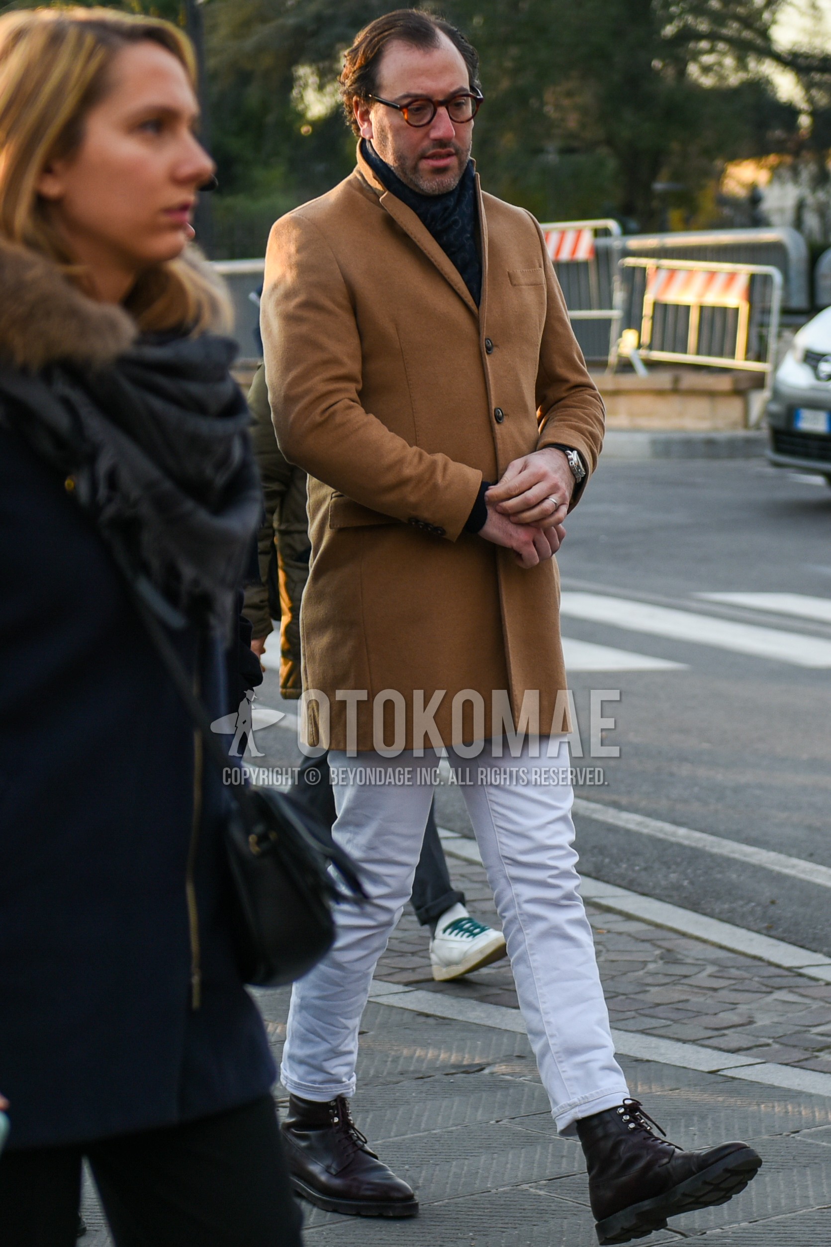 Men's winter outfit with brown tortoiseshell glasses, black scarf scarf, beige plain chester coat, white plain cropped pants, white plain cotton pants, brown  boots.