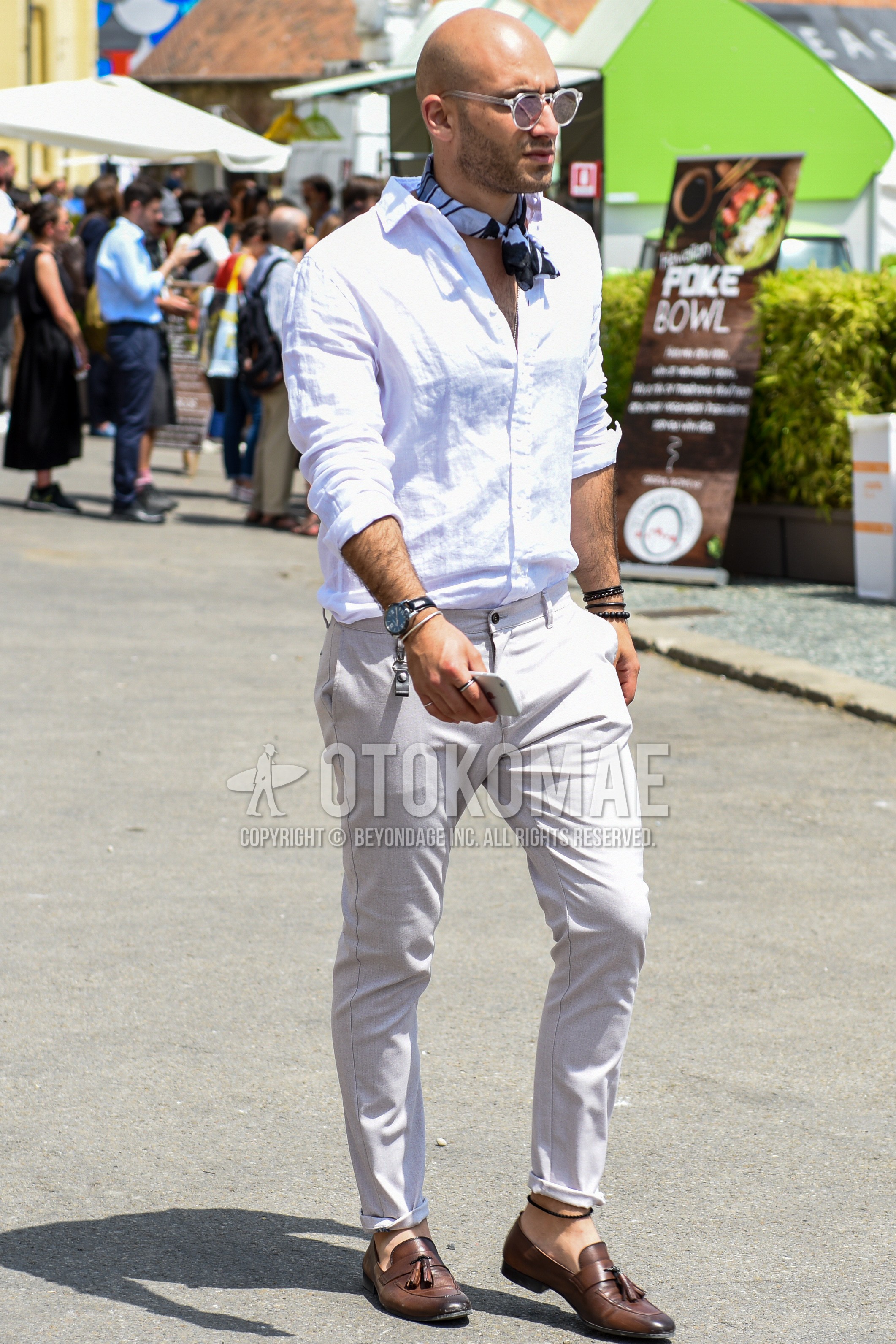 Men's spring summer outfit with clear plain sunglasses, white scarf bandana/neckerchief, white plain shirt, white plain chinos, brown tassel loafers leather shoes.