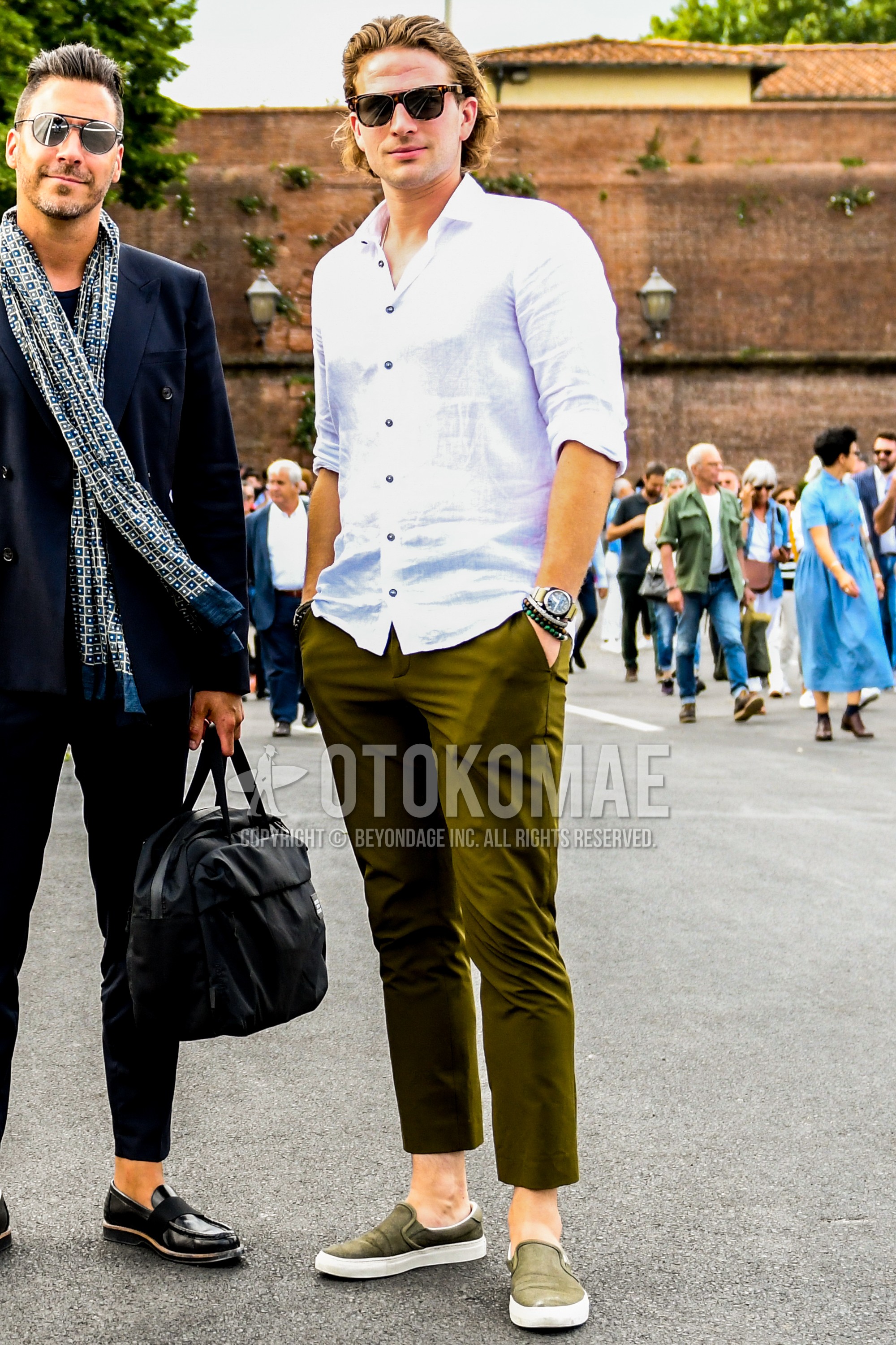 Men's spring summer autumn outfit with white plain shirt, olive green plain ankle pants, olive green slip-on sneakers.