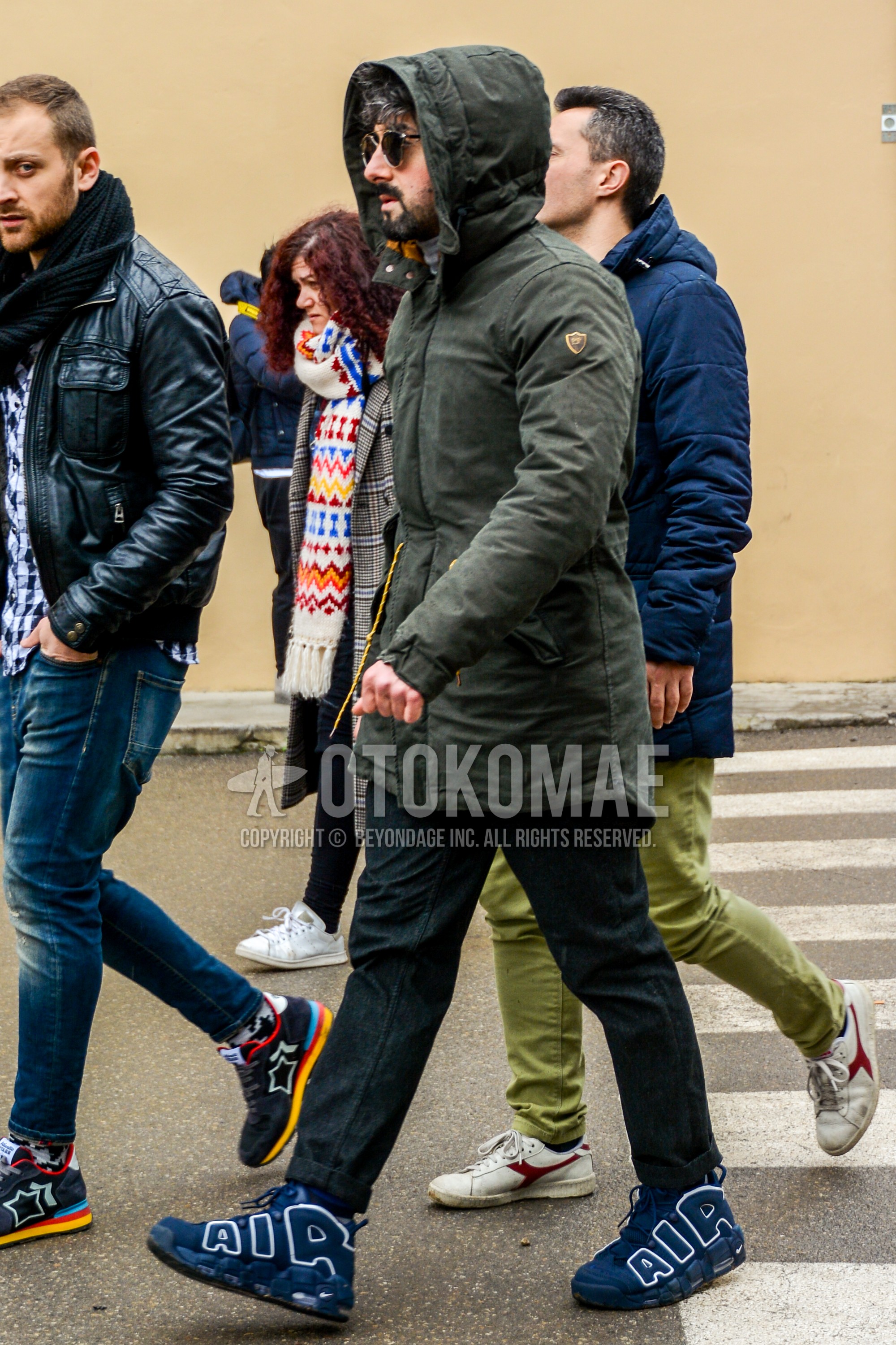 Men's winter outfit with olive green plain hooded coat, black plain cotton pants, navy high-cut sneakers.